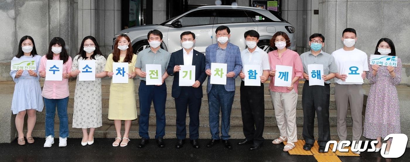 본문 이미지 - 충북도가 15일 도청이 보유한 무공해 자동차 12대에 홍보물을 부착하는 행사를 했다. 직원들이 전기차와 수소차 이용을 홍보하고 있다.(충북도 제공).2020.7.15.ⓒ 뉴스1