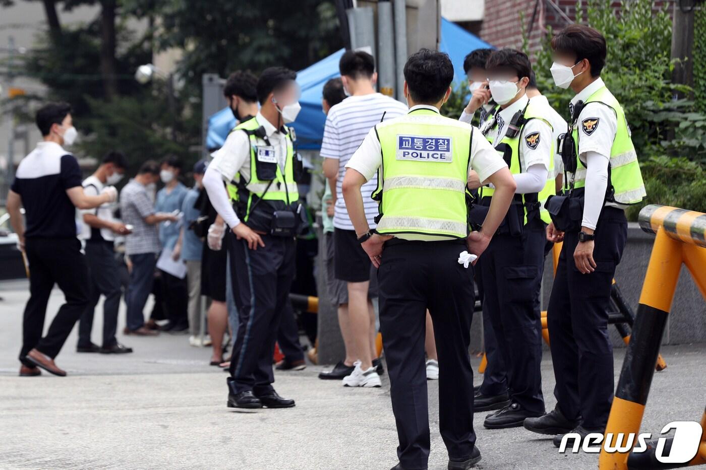 본문 이미지 - 사랑제일교회발(發) 신종 코로나바이러스 감염증(코로나19) 확진자가 확산하고 있는 가운데 18일 오후 서울 종로구 보건소에 설치된 선별진료소에서 경찰관과 사민들이 검사를 기다리고 있다.2020.8.18/뉴스1 ⓒ News1 황기선 기자