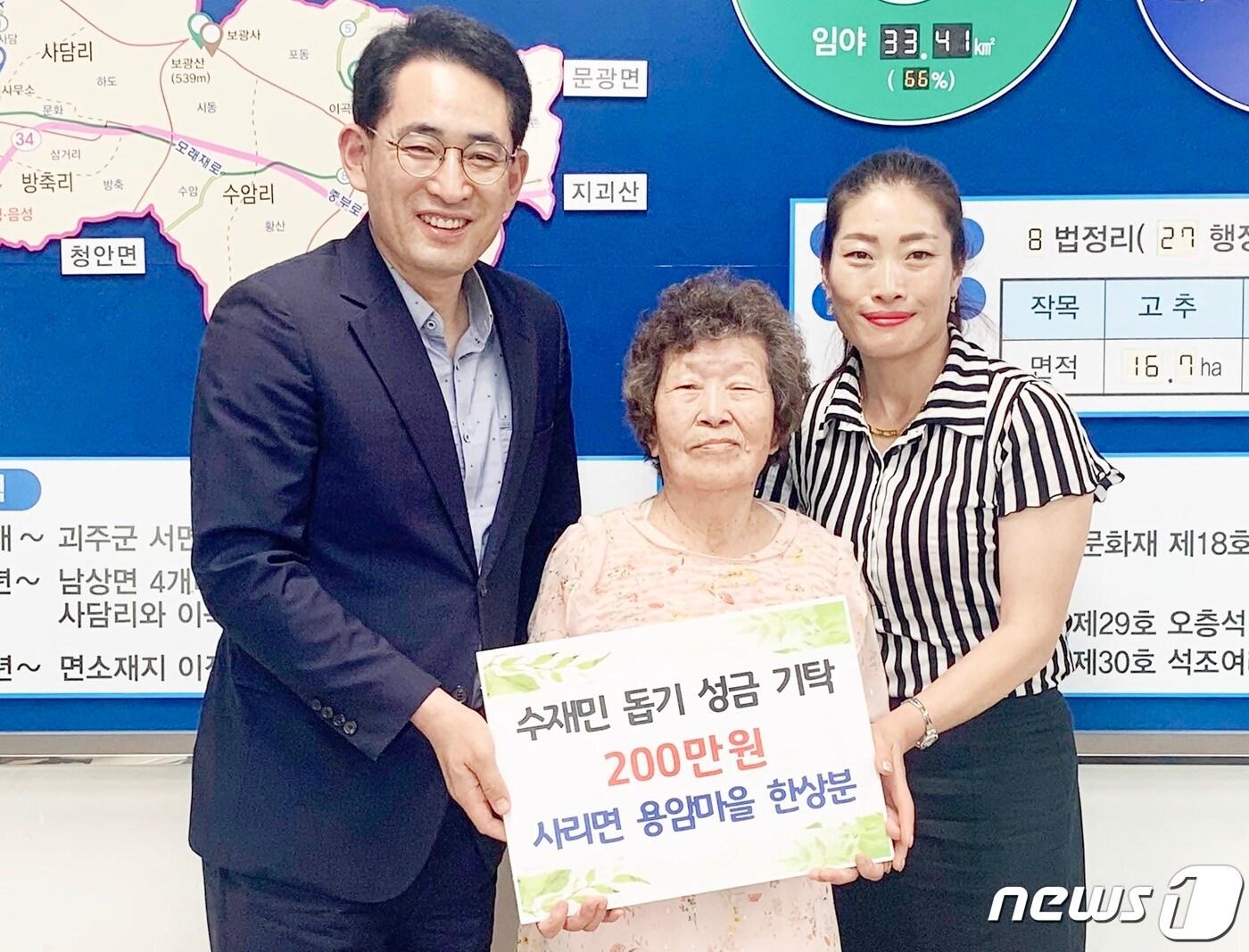 본문 이미지 - 괴산군 사리면 한상분씨가 주민자치센터에 수재민을 위해 써달라며 절약해 모은 200만원을 전달하고 있다.(괴산군 제공)ⓒ 뉴스1