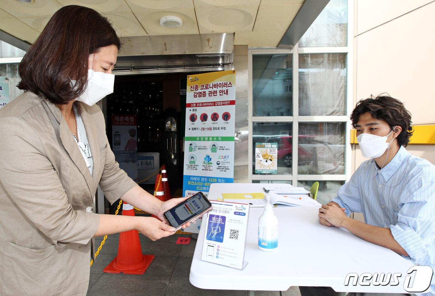 본문 이미지 - 지난 9월1일 서울 동작구 노량진2동주민센터를 방문한 주민이 스마트폰 QR코드 스캔으로 본인인증 출입명단을 등록하고 있다. (동작구청 제공) 2020.9.1/뉴스1