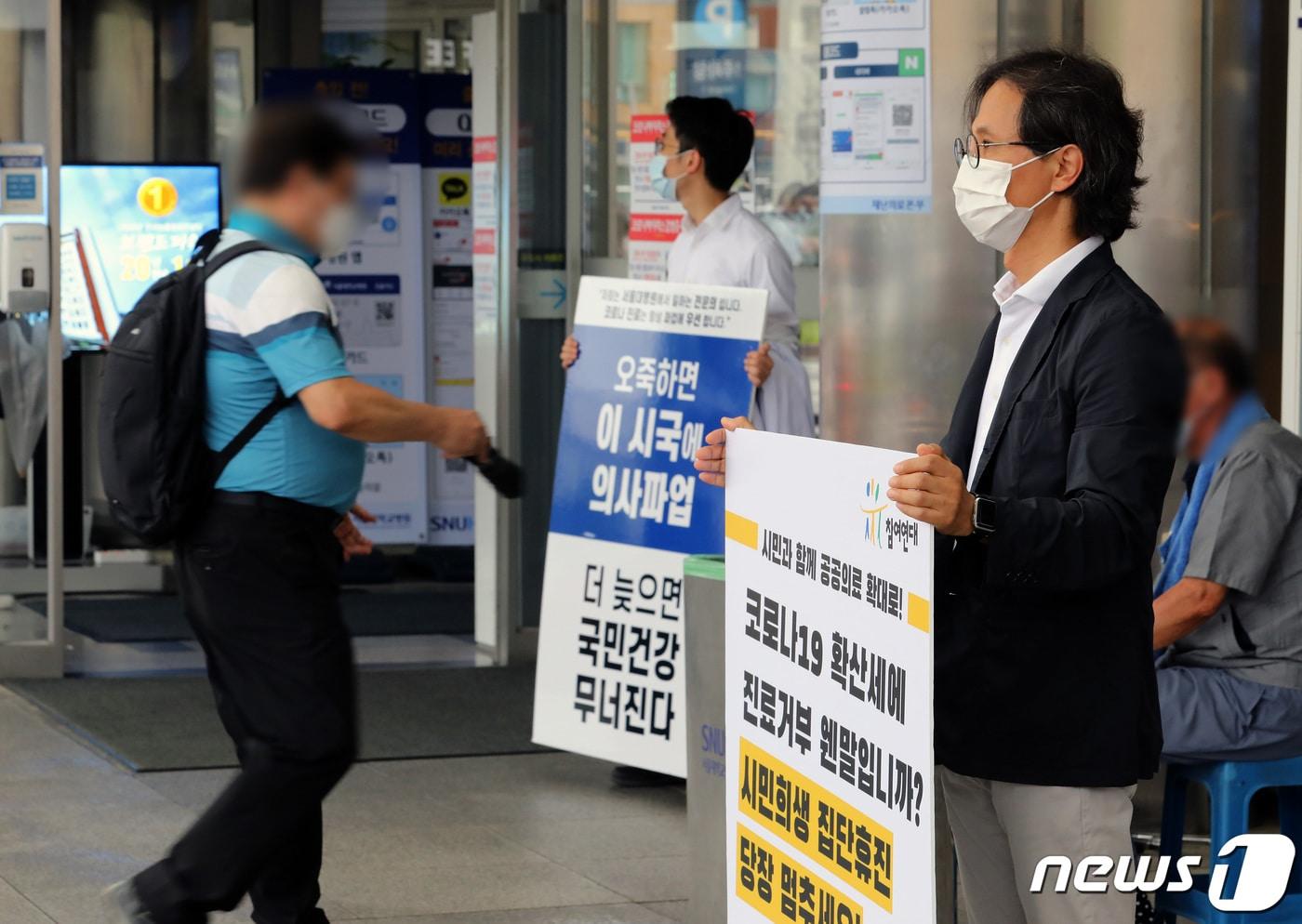 본문 이미지 - 2일 오전 서울 종로구 서울대병원 본관 앞에서 한 전공의가 정부의 의료정책을 반대하는 내용이 적힌 피켓을 들고 있다. 앞쪽으로는 윤홍식 참여연대 사회복지위원장이 의사협회의 진료거부 철회 촉구 1인 시위를 하고 있다. 2020.9.2/뉴스1 ⓒ News1 이재명 기자