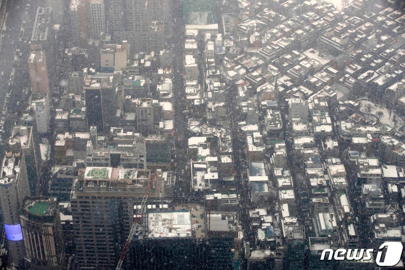 서울 동남·서남권, 경기도 광명·시흥에 대설주의보가 발효된 12일 오후 서울 송파구 롯데월드타워 전망대 서울스카이에서 바라본 도심에 눈이 날리고 있다. 2021.1.12/뉴스1 ⓒ News1 이승배 기자