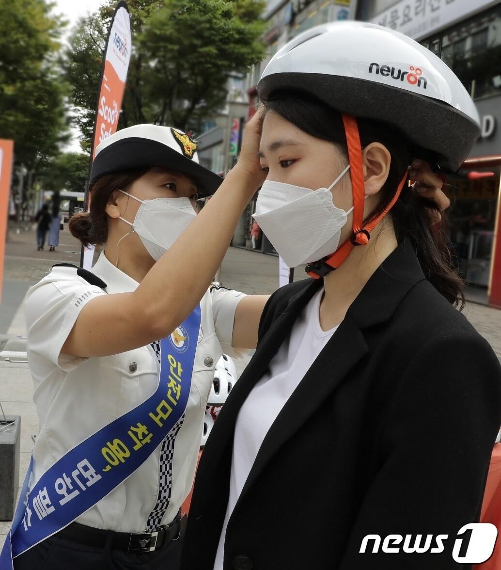 본문 이미지 - 경기도 안양시 범계역 일대에서 뉴런 모빌리티와 안양동안경찰서가 ‘헬멧 안전주간 2021’을 맞이해 전동킥보드 안전 헬멧 사용을 장려하는 캠페인을 진행하고 있다. 동안경찰서 경찰관이 시민에게 안전 헬멧 바로 쓰는 법을 알려주고 있다. (뉴런 모빌리티 제공) 2021.10.1/뉴스1