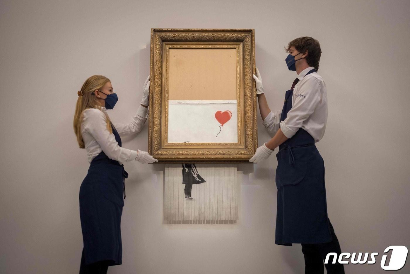 본문 이미지 - 14일(현지시간) 런던 소더비 경매에서 뱅크시의 '풍선과 소녀' 작품이 1858만2000파운드에 낙찰됐다. 뱅크시의 작품 중 역대 최고가 기록이다. ⓒ AFP=뉴스1 ⓒ News1 신윤하 기자