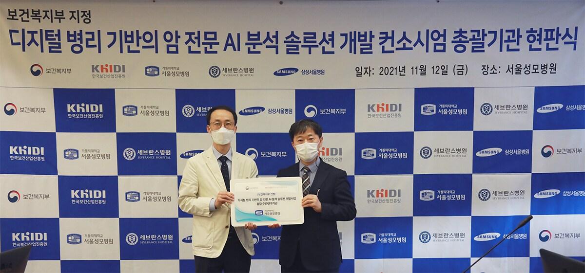 본문 이미지 - 정찬권 서울성모병원 병리과 교수(왼쪽)와 이형훈 보건산업정책국장이 현판식 기념촬영을 하고 있다(사진제공=서울성모병원) ⓒ 뉴스1