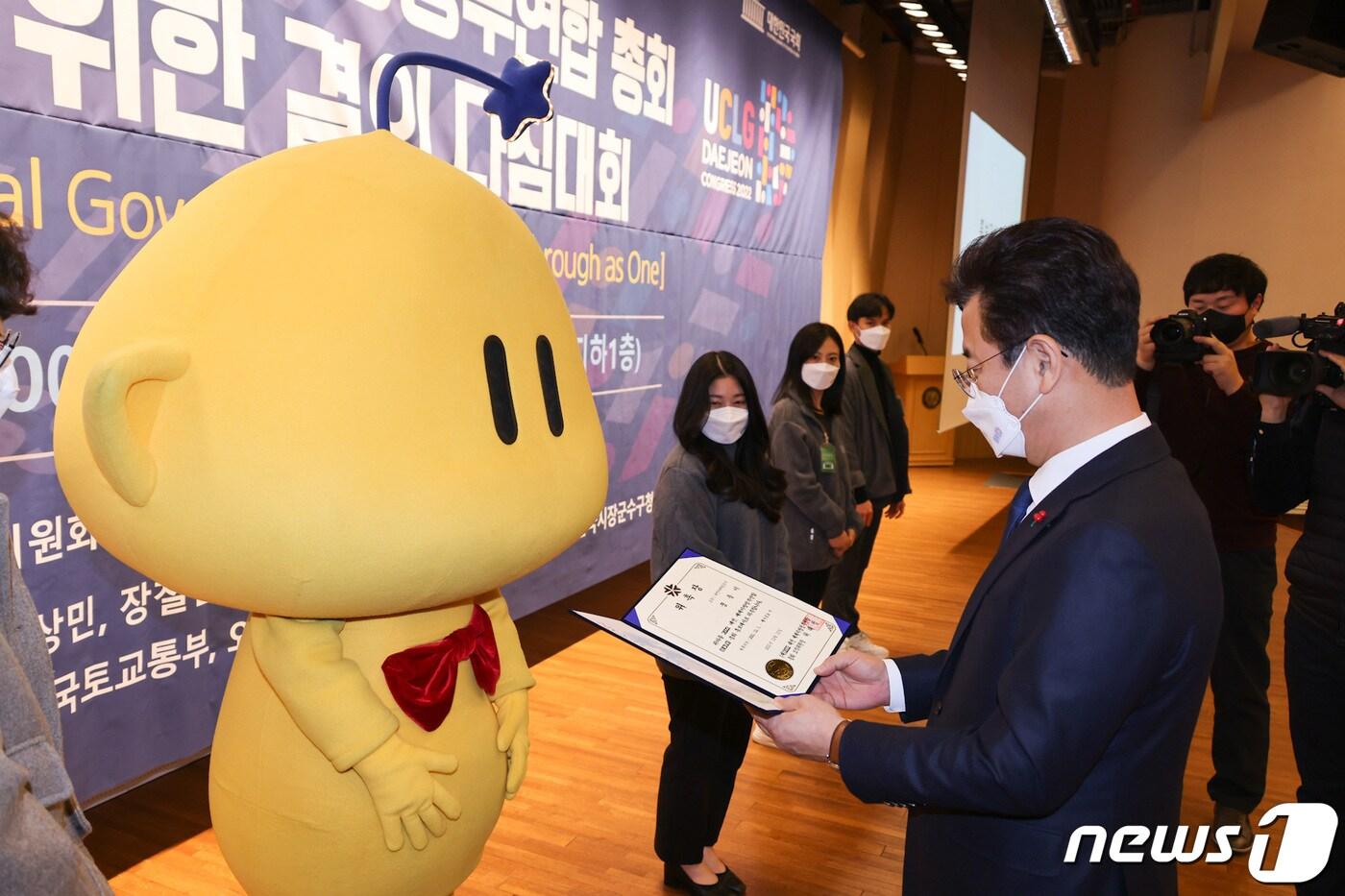 본문 이미지 - 13일 국회도서관에서 열린 ‘2022 대전 UCLG 총회 성공 개최 결의대회’에서 허태정 시장이 1993년 대전엑스포 마스코트 ‘꿈돌이’를 홍보대사로 위촉하고 있다. (대전시 제공) ⓒ뉴스1