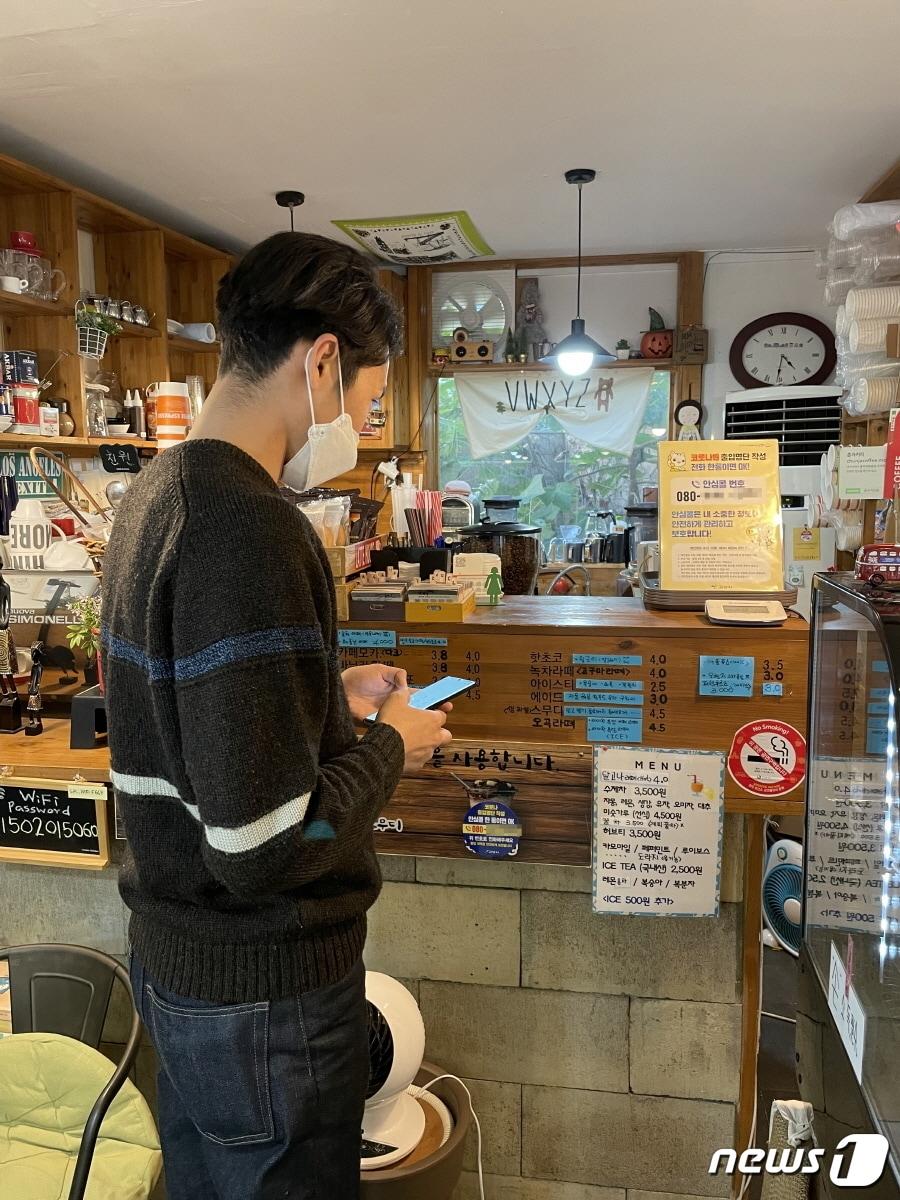 본문 이미지 - 경기 고양시가 시스템 과부하로 논란이 되고 있는 방역패스 대신 전화 한통화로 출입확인과 백신접종 여부를 확인할 수 있는 &#39;안심 방역패스&#39;를 개발, 시범운영을 준비중이다. 고양시의 한 매장에서 안심콜로 출입을 등록하고 있는 손님. &#40;고양시청 제공&#41; ⓒ 뉴스1