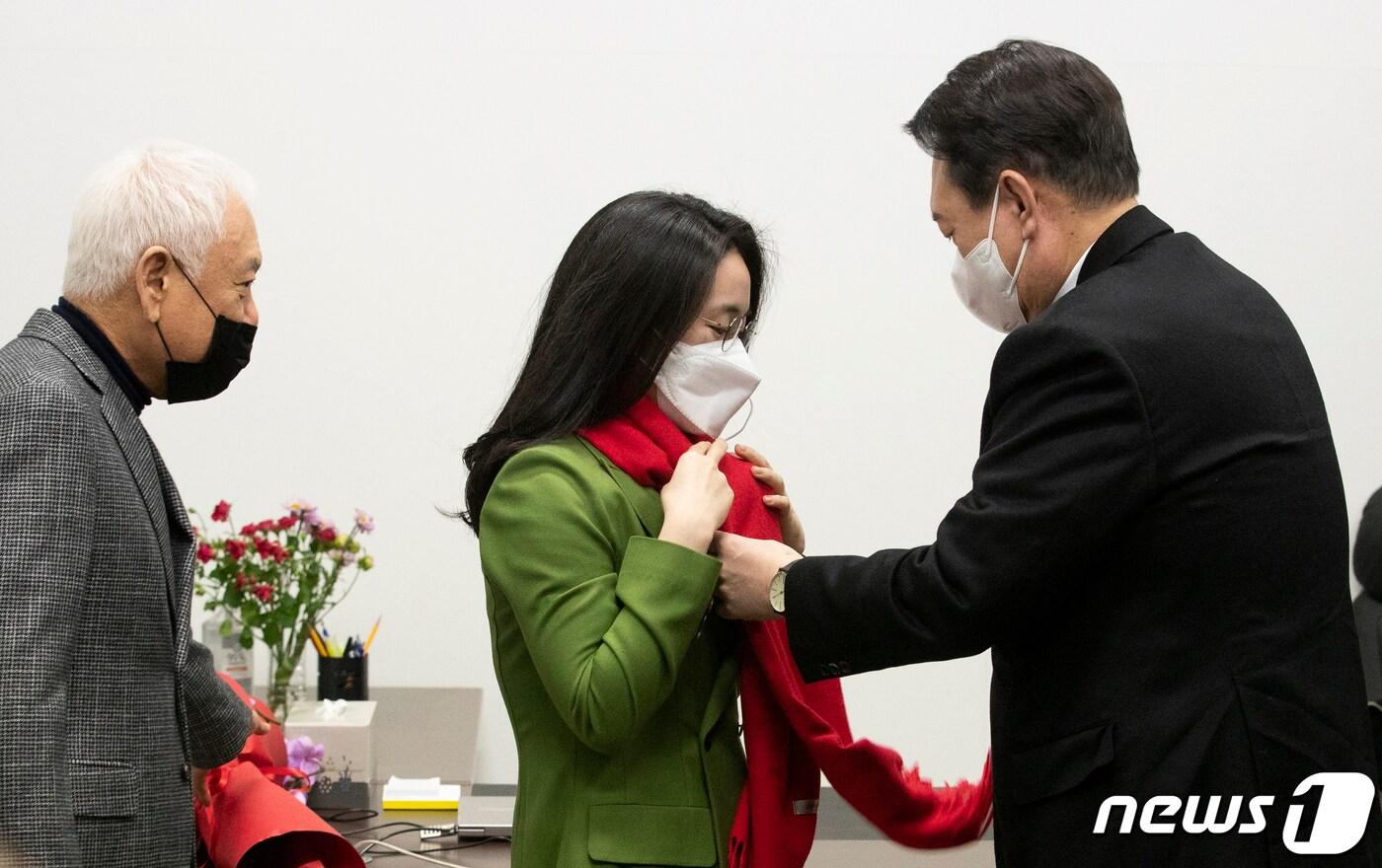 본문 이미지 - 윤석열 국민의힘 대선 후보가 20일 서울 여의도 새시대준비위원회 위원장실에서 열린 영입인사 환영식에서 신지예 한국여성정치 네트워크 대표에게 환영 목도리를 걸어주고 있다. 2021.12.20/뉴스1 ⓒ News1 오대일 기자