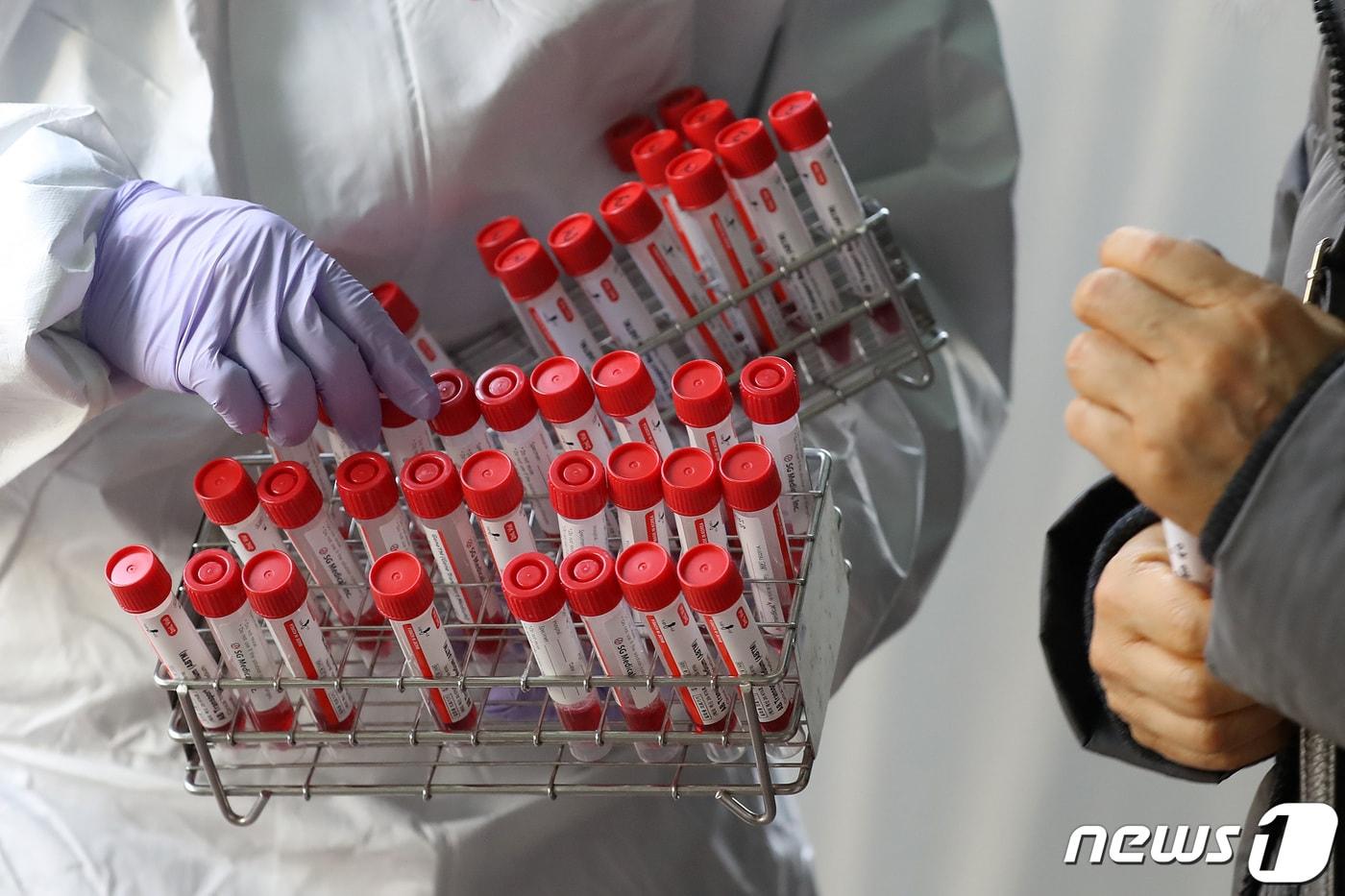 21일 대구 중구보건소 선별진료소에서 의료진이 코로나19 진단검사를 위해 방문한 시민의 신원을 확인한 뒤 검체 채취용 수송배지를 나눠주고 있다. 2021.12.21/뉴스1 ⓒ News1 공정식 기자