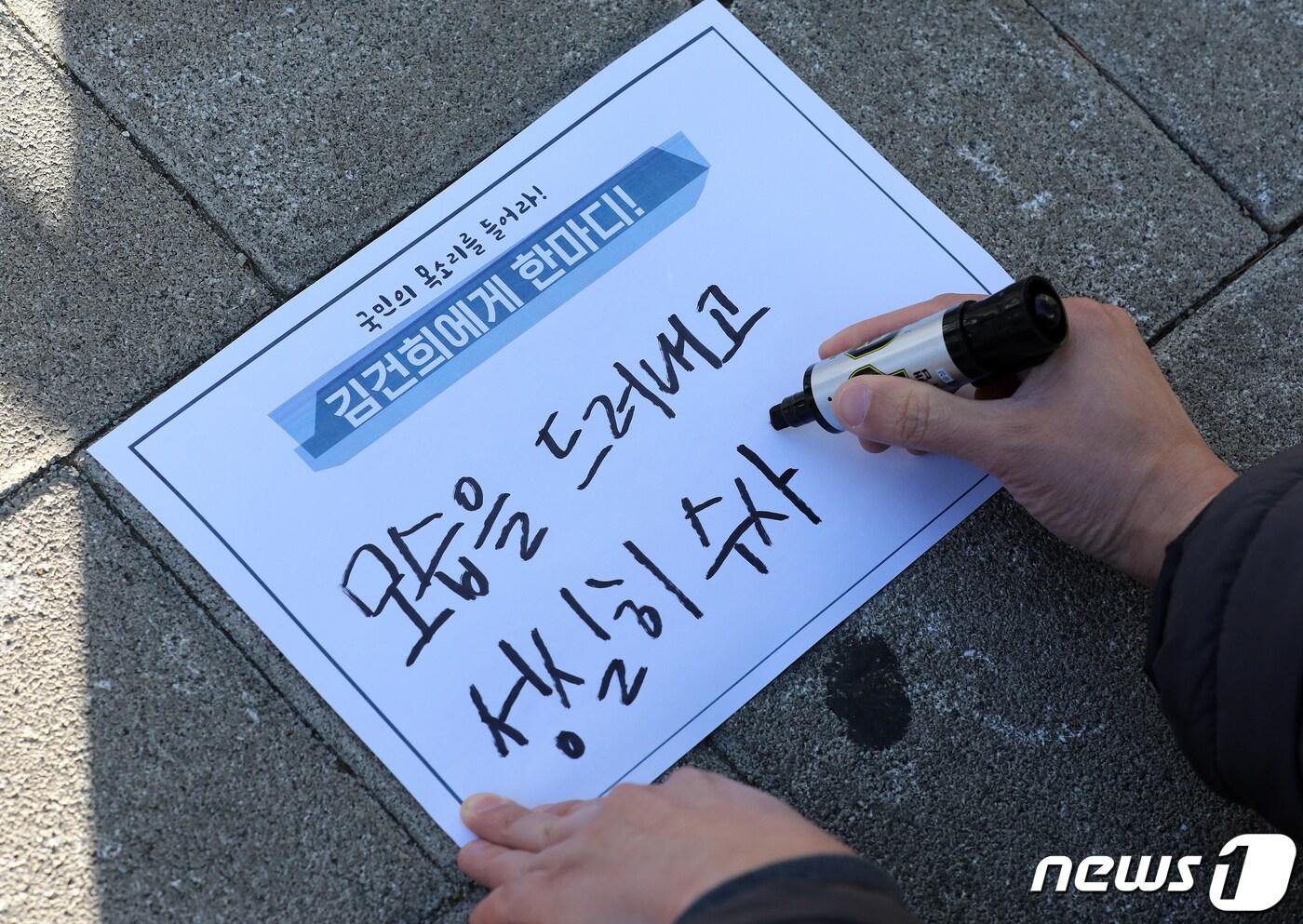 대학생 대선실천단 학생이 22일 오후 서울 서초구 서초동 아크로비스타 앞에서 열린 ‘허위경력은 범죄다! 김건희는 자수하라!’ 구속 촉구 집회에서 메시지를 적고 있다. 2021.12.22/뉴스1 ⓒ News1 김진환 기자