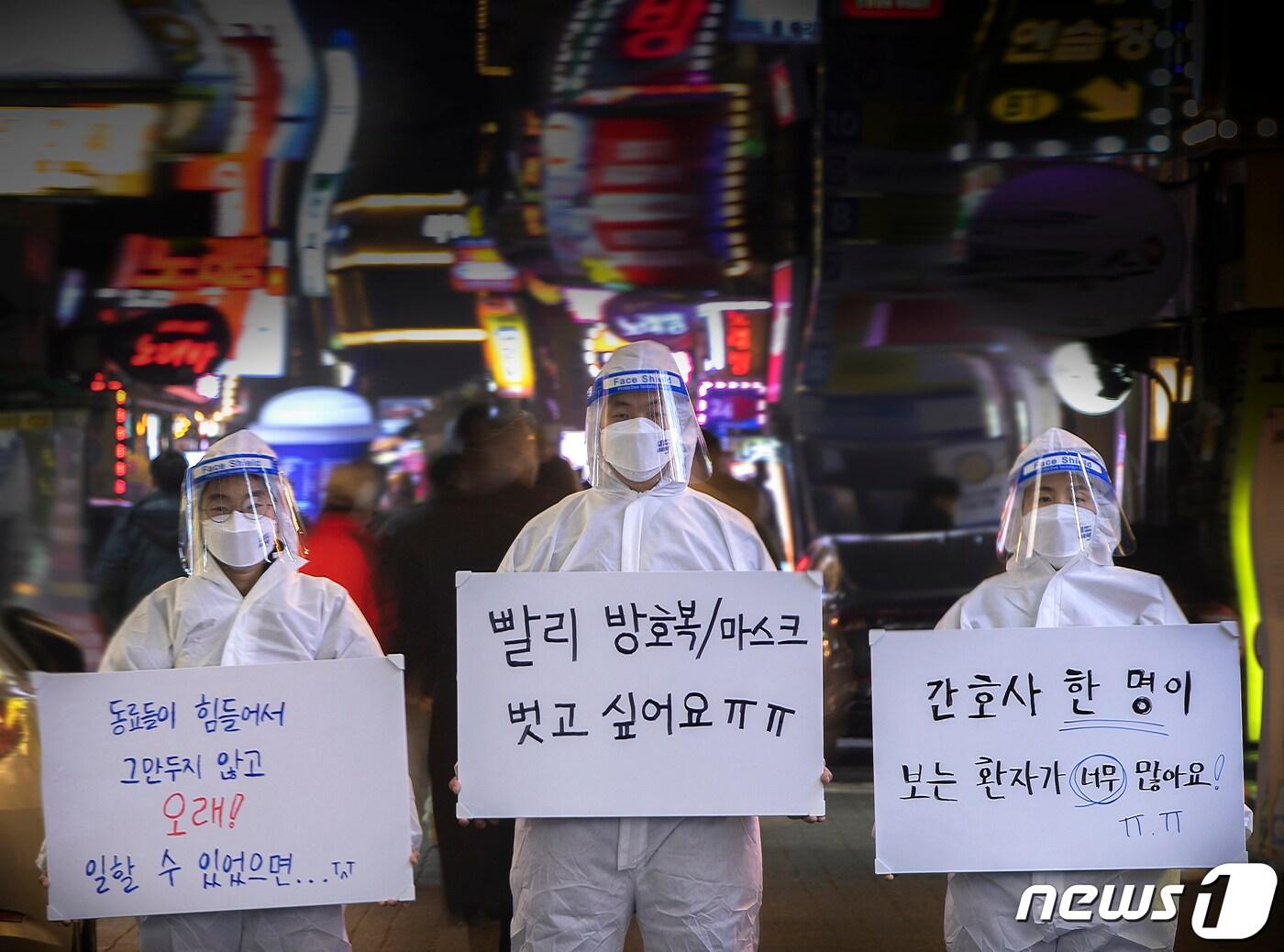 본문 이미지 - 의료진이 서울 종로 유흥가에 새해 소원이 쓰인 플래카드를 들고 서 있다. 왼쪽부터 공공운수노조 의료연대본부 소속 김민정 간호사, 김별샘 병원노동자, 김혜정 간호사. 2021.12.29/뉴스1 ⓒ News1 신웅수 기자