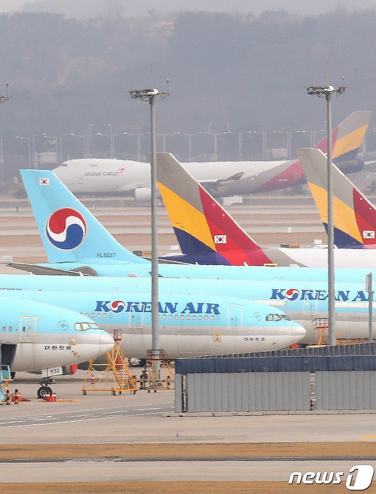 본문 이미지 - 공정거래위원회가 연내 대한항공과 아시아나항공 인수·합병(M&A) 심사를 마무리 하고 이르면 내년 초 결론을 낼 전망이다. 대한항공과 아시아나항공의 합병에 대해서는 조건부 승인 가능성이 높게 점쳐진다. 독과점 발생 우려가 있는 노선이나 슬롯 사업권의 일부 매각 등을 조건으로 승인 결론을 내릴 것으로 관측된다. 27일 인천국제공항 주기장에 대한항공과 아시아나 여객기가 세워져 있다. 2021.12.27/뉴스1 ⓒ News1 임세영 기자