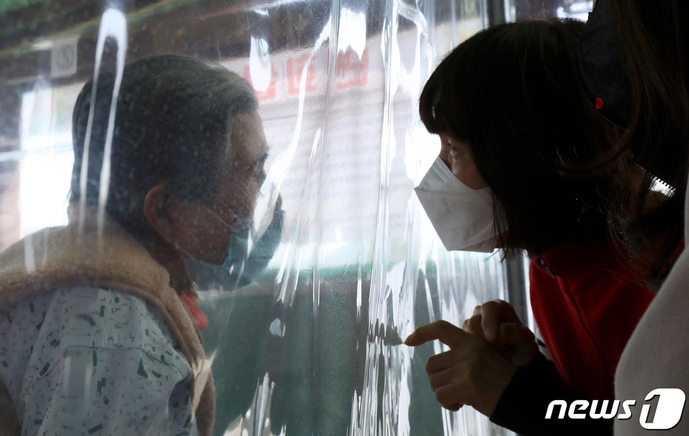 본문 이미지 - 한 요양병원에 설치된 비닐 면회실에서 며느리가 비닐막 너머 앉은 시어머니를 면회하고 있다. 2021.2.12/뉴스1 ⓒ News1 윤일지 기자