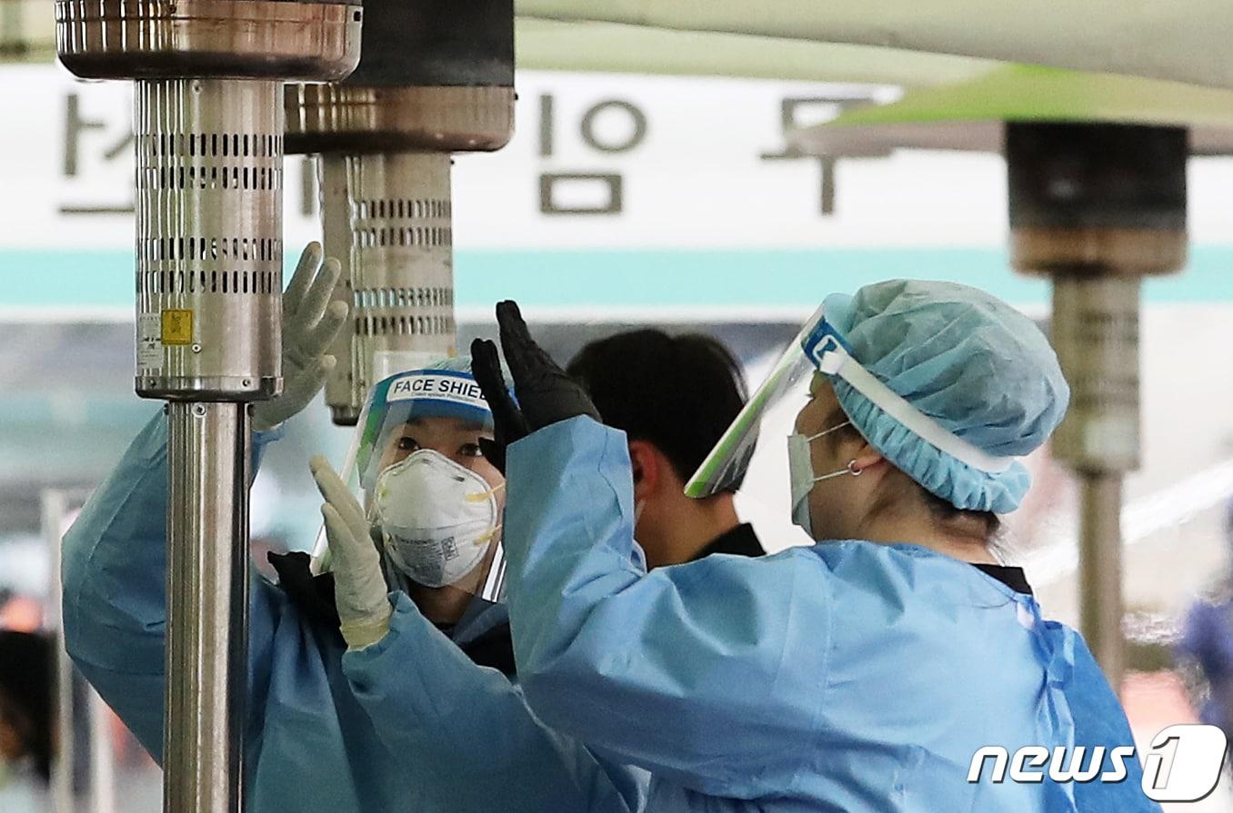 본문 이미지 - 전국 대부분 지역에 한파 특보가 내려진 16일 오전 서울 중구 서울역 광장에 마련된 신종코로나바이러스 감염증(코로나19) 임시 선별진료소에서 의료진이 언 손을 녹이고 있다. 질병관리청 중앙방역대책본부는 이날 0시 기준 신규 확진자가 전날보다 113명 증가한 457명 발생했다고 밝혔다. 2021.2.16/뉴스1 ⓒ News1 오대일 기자