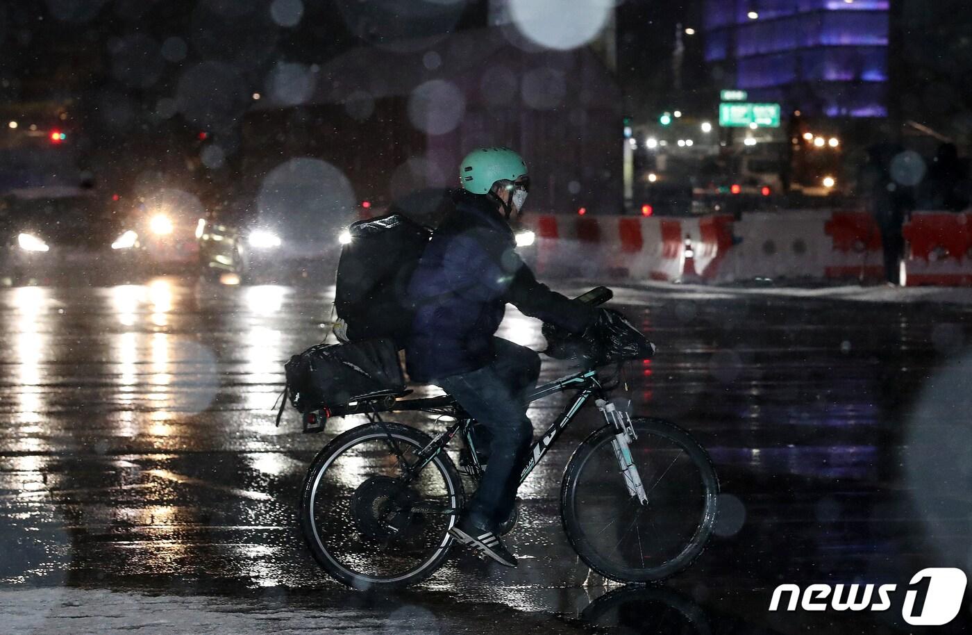 서울 전역과 경기북부 지역에 대설주의보가 내려진 3일 오후 서울 종로구 광화문역 인근 세종로에서 한 배달원이 자전거를 타고 횡단보도를 건너고 있다. 2021.2.3/뉴스1 ⓒ News1 김진환 기자