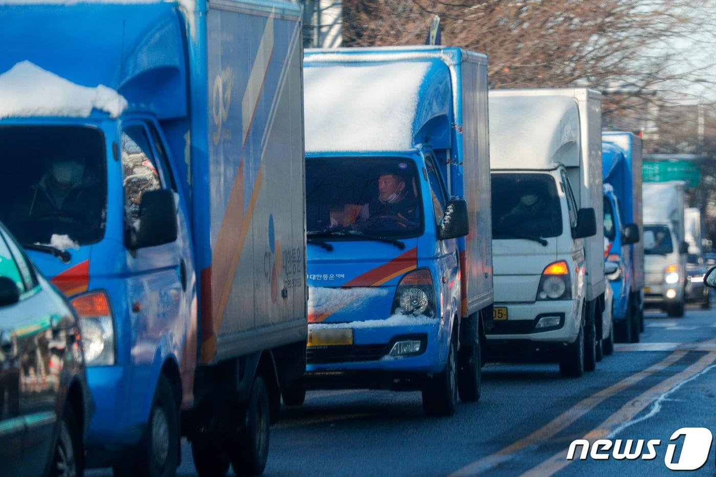 CJ대한통운, 롯데택배, 한진택배, 로젠택배 등 4개 택배사 대리점연합회가 4일 오전 서울 여의도 국회의사당 앞에서 사회적 합의안에 대한 입장을 발표하는 중 이를 지지하는 택배차량들이 국회 앞을 지나고 있다. 2021.2.4/뉴스1 ⓒ News1 안은나 기자