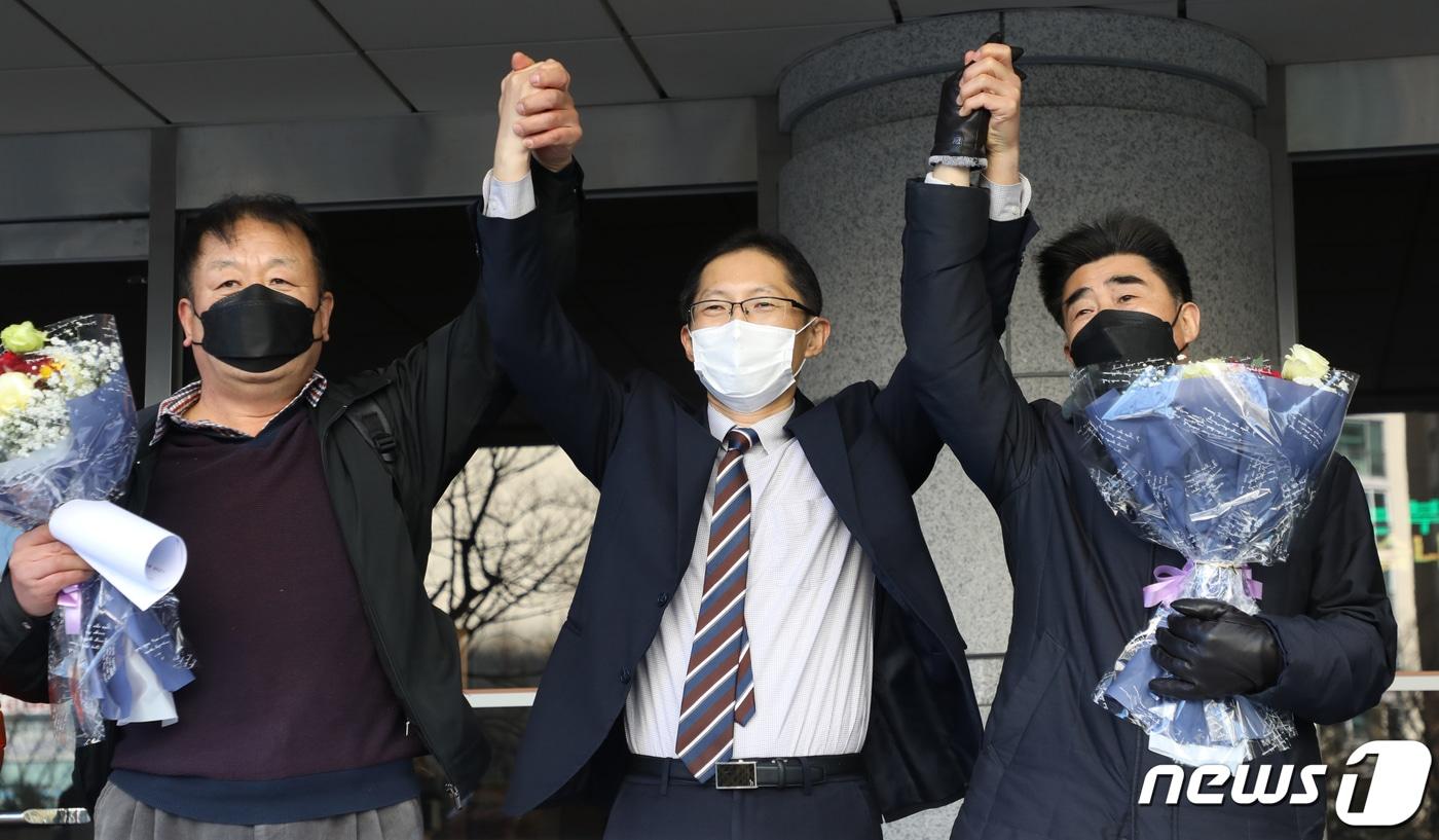 ‘낙동강변 살인사건’ 범인으로 지목돼 21년간 옥살이를 한 장동익씨와 최인철씨가 4일 오전 부산 연제구 부산고등법원에서 열린 재심 선고 공판 후 박준영 변호사와 손을 들어보이고 있다. 2021.2.4/뉴스1 ⓒ News1 여주연 기자
