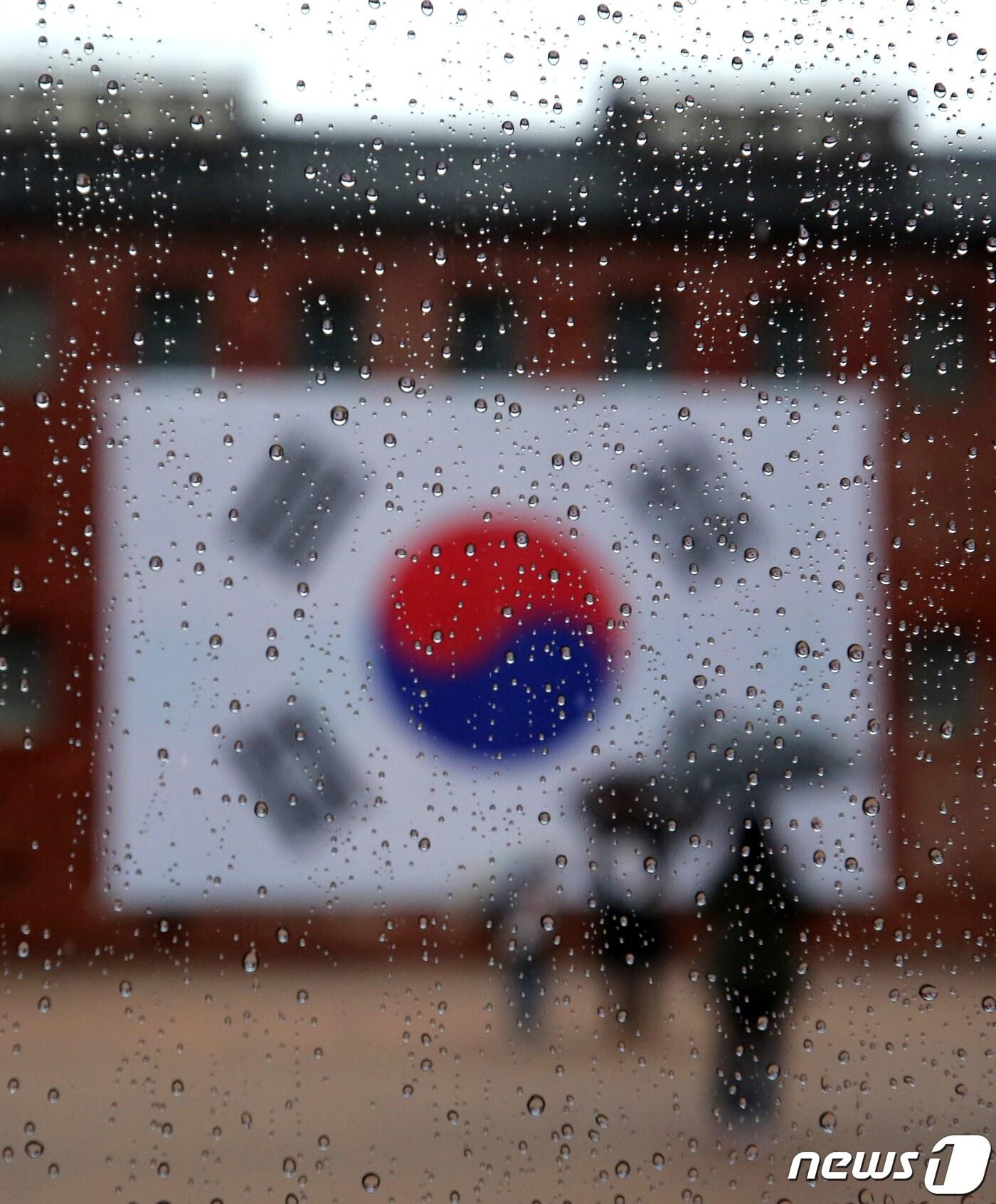 본문 이미지 - 제102주년 3·1절인 1일 오후 서울 서대문형무소역사관에 설치된 대형 태극기 앞 유리에 빗물이 맺혀있다. 이날 서대문형무소역사관 관람은 신종 코로나바이러스 감염증&#40;코로나19&#41; 감염 예방 및 확산 방지를 위해 사전예약제로 승인된 관람객에 한해 진행됐다. 2021.3.1/뉴스1 ⓒ News1 구윤성 기자