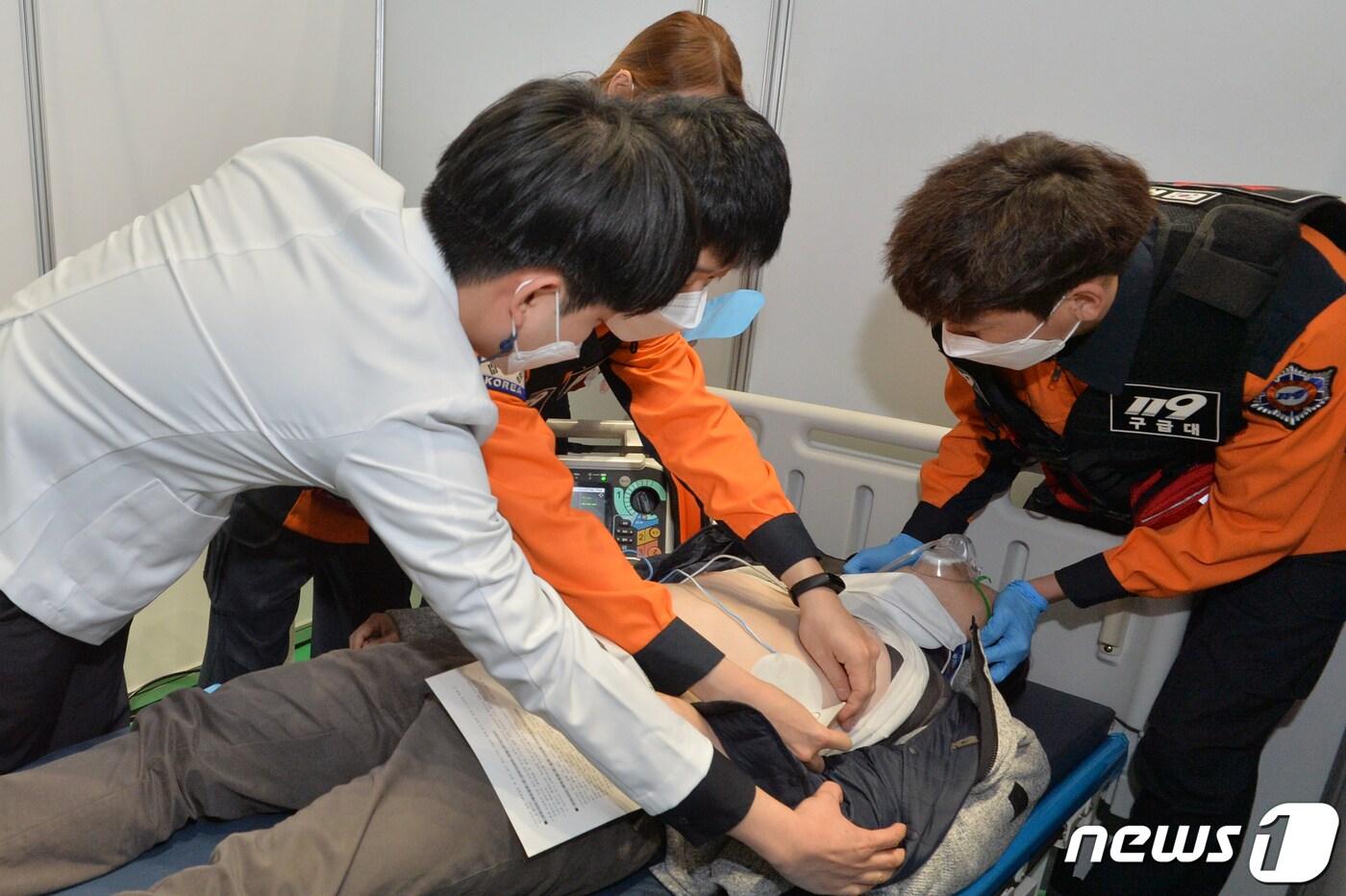 본문 이미지 - 경북 포항남부소방서 119구급대원들이 지난 3월 남구 실내체육관에서 실시된 코로나19 화이자 백신 접종 모의훈련에서 접종 후 이상 반응을 보인 시민의 건강 상태를 확인하고 있다. 2021.3.18/뉴스1 ⓒ News1 최창호 기자