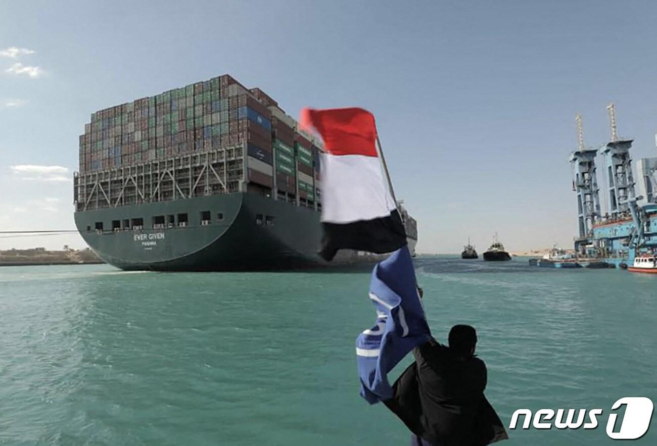본문 이미지 - 지난 3월 29일(현지시간) 이집트 수에즈 운하에서 좌초됐던 초대형 컨테이너선 에버기븐호가 부양에 성공하자 한 이집트인이 국기를 흔들고 있다. ⓒ AFP=뉴스1 ⓒ News1 우동명 기자