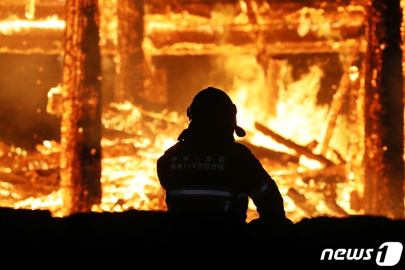 5일 오후 6시 50분께 전북 정읍시 내장사 대웅전에서 방화로 추정되는 화재가 발생해 불길이 치솟고 있다. 한 소방관이 불길을 잡기 위해 안간힘을 쓰고 있다.(정읍시 제공) 2021.3.5/뉴스1 ⓒ News1 박제철 기자