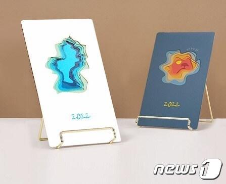 본문 이미지 - 전북 부안군은 지역의 문화와 관광자원을 대표하는 관광기념품과 패스트푸드를 선정했다. 부안의 대표적 명소인 채석강의 해식동굴과 솔섬을 모티브로 여러 겹의 색깔달력을 겹쳐 넘길 때마다 색이 변하는 ‘세월의 겹겹이 달력’ⓒ 뉴스1