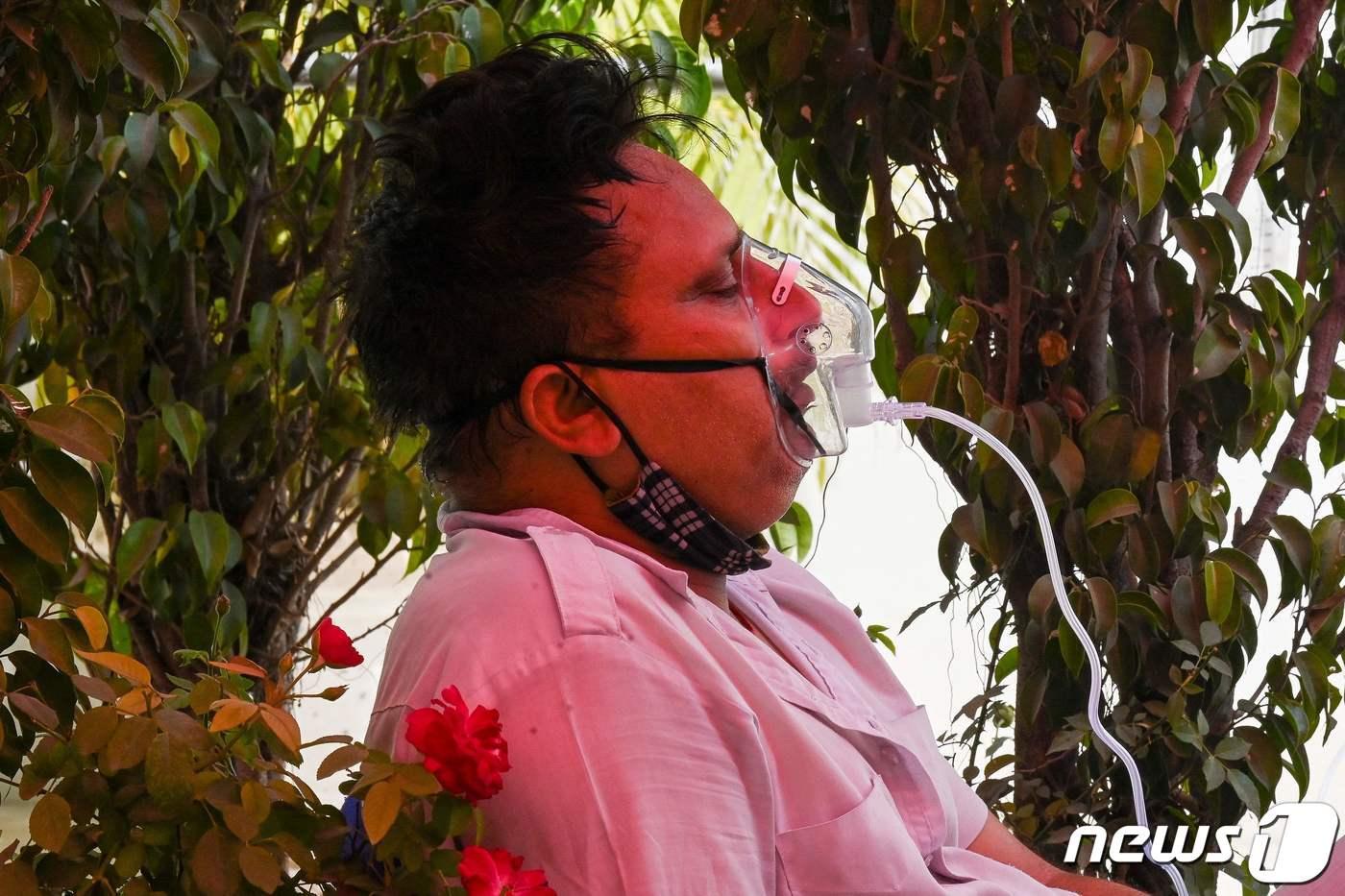 인도 가지아바드 길가에 설치된 임시 코로나19 치료소에서 2021년 4월 28일 한 환자가 산소마스크에 의지해 호흡을 이어가는 모습. ⓒ AFP=뉴스1 ⓒ News1 최서윤 기자