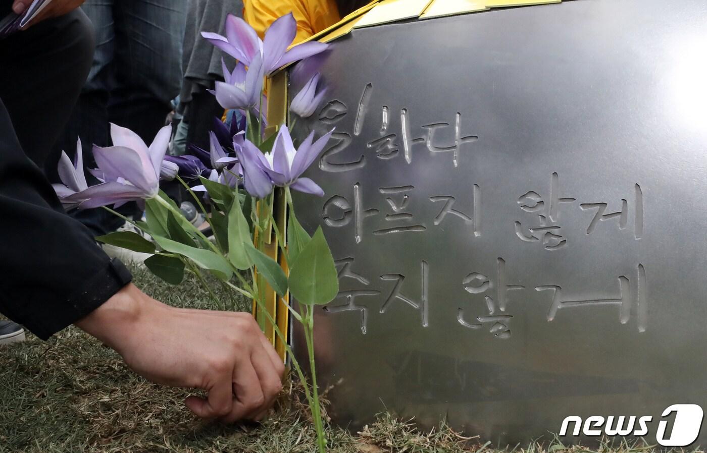 28일 충남 태안시 태안화력발전소 정문에서 열린 '청년비정규직 故 김용균 추모조형물 제막식'에서 참석자들이 故김용균를 추모하며 조형물 앞에 꽃을 꽂고 있다. 2021.4.28/뉴스1 ⓒ News1 장수영 기자