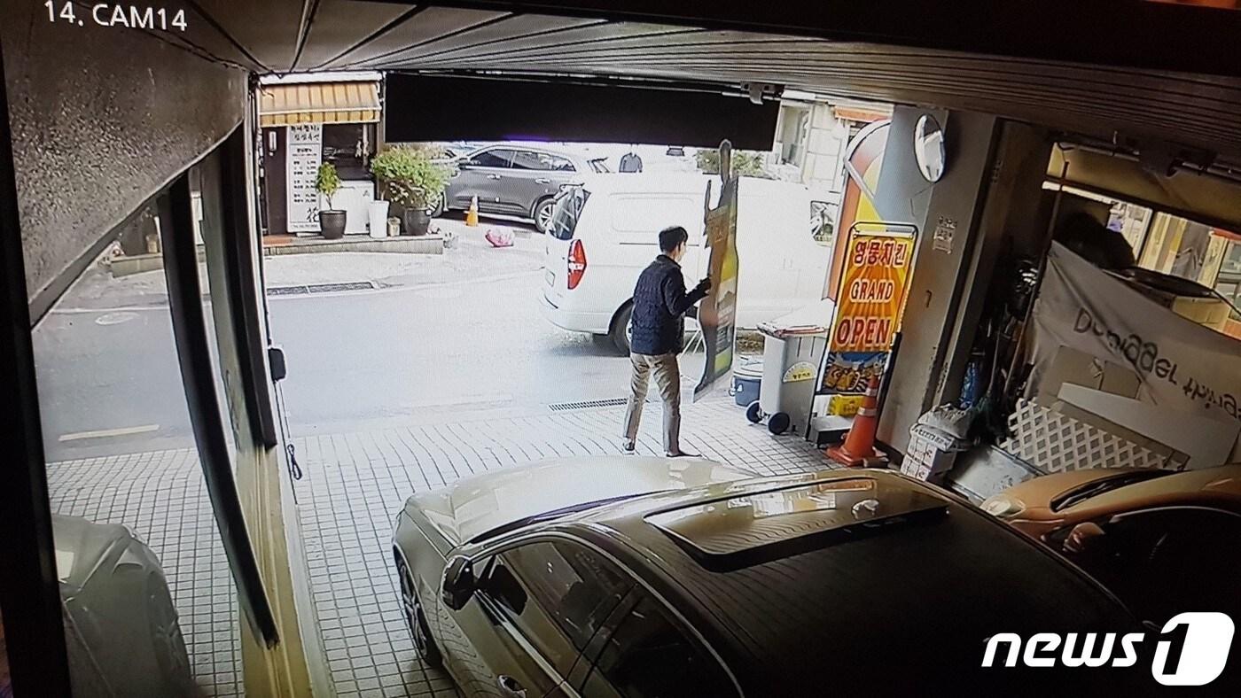 본문 이미지 - 정체 불상의 사람이 식당 앞에 승합차를 세운 뒤 오비맥주 '한맥' 입간판을 무단으로 수거해 트렁크에 실고 있다. (오비맥주가 입수해 경찰에 증거로 제출한 CCTV 영상 일부. ⓒ 뉴스1