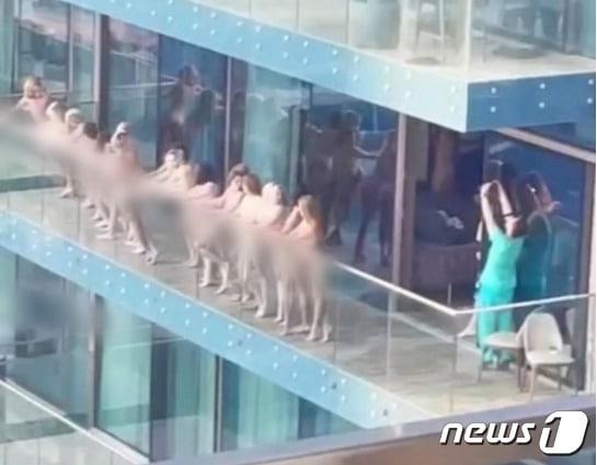 본문 이미지 - 두바이 마리나 지구 발코니에서 여성 십수명이 나체 촬영을 하는 모습. - 트위터 갈무리