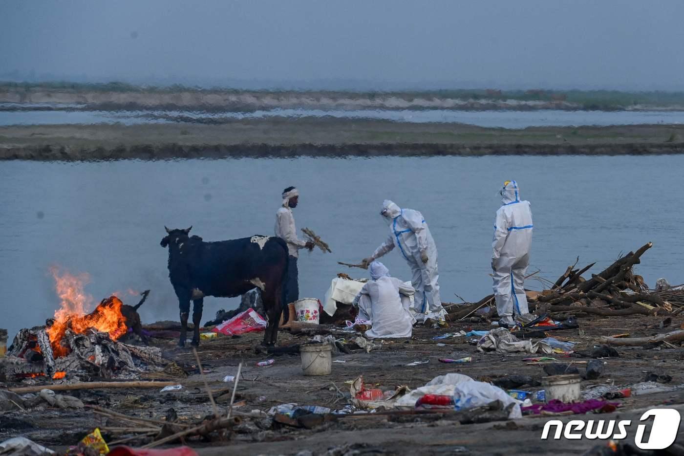 지난 5일 갠지스 강둑에서 보호복을 입은 친척들이 코로나19로 사망한 가족을 화장하기 전 마지막 의식을 치르는 모습.ⓒ AFP=뉴스1