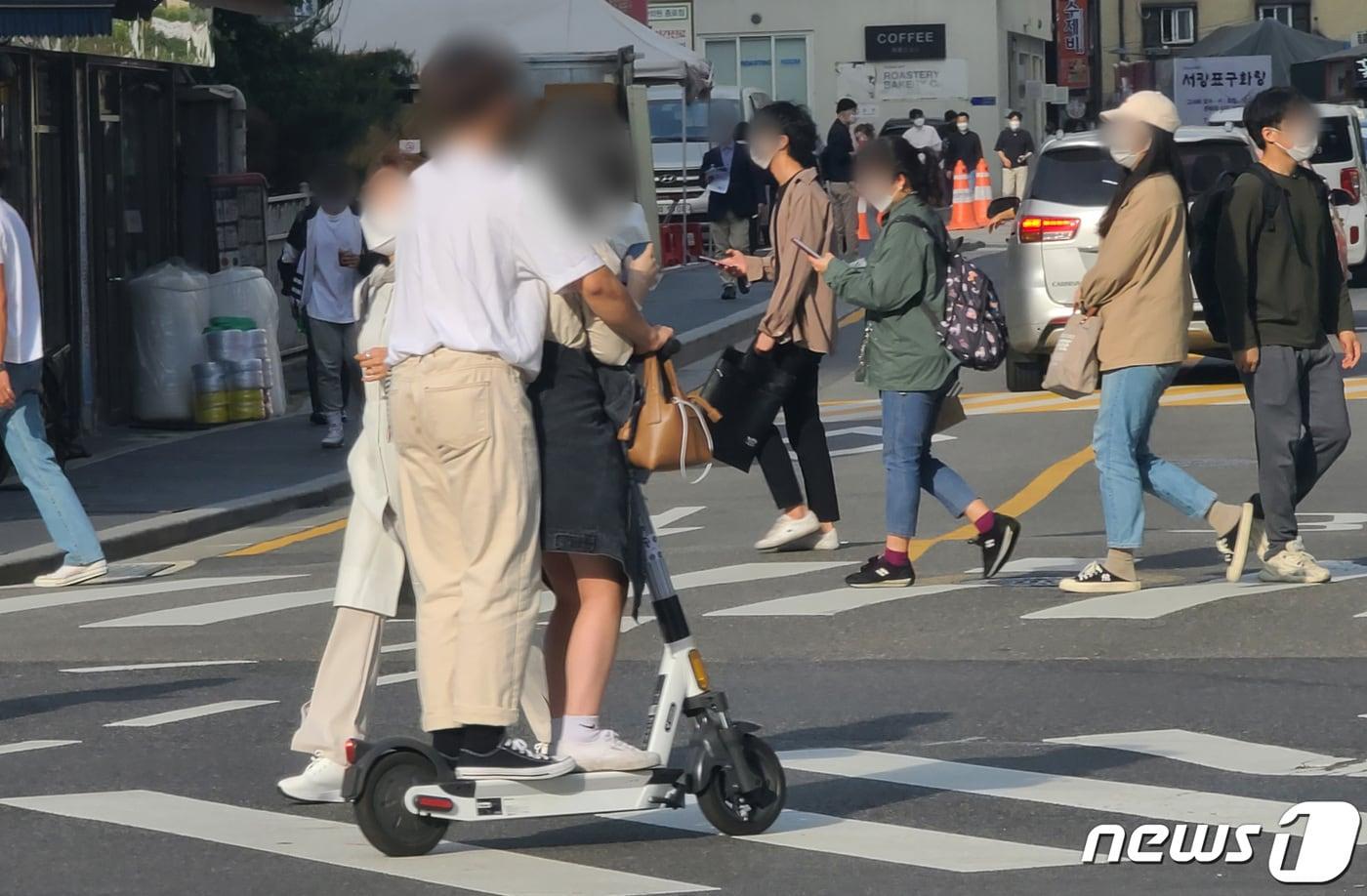 전동킥보드 등 개인형 이동장치(PM)의 이용 규제를 강화하는 개정 도로교통법 시행을 이틀 앞둔 11일 서울의 한 횡단보도에서 시민들이 전동킥보드에 동승하고 있다.2021.5.11/뉴스1 ⓒ News1 허경 기자