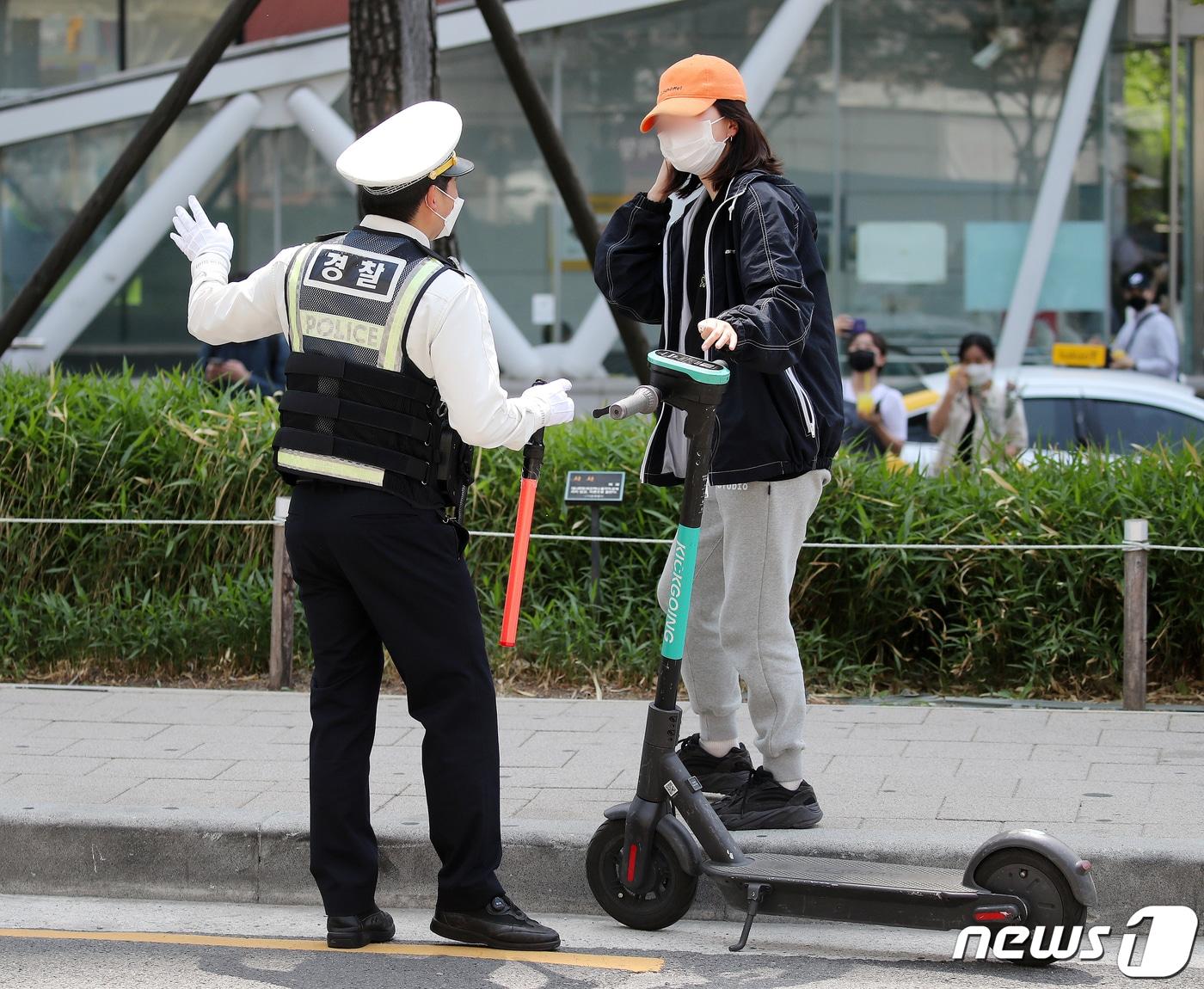 본문 이미지 - 전동킥보드 등 개인형 이동장치(PM)의 이용 규제를 강화하는 개정 도로교통법 시행이 시작된 13일 오후 서울 마포구 홍대입구역 인근 인도에서 마포경찰서 경찰들이 헬멧 없이 전동킥보드를 이용하는 시민에게 재개정 관련 내용 홍보 및 계도를 하고 있다.2021.5.13/뉴스1 ⓒ News1 김진환 기자