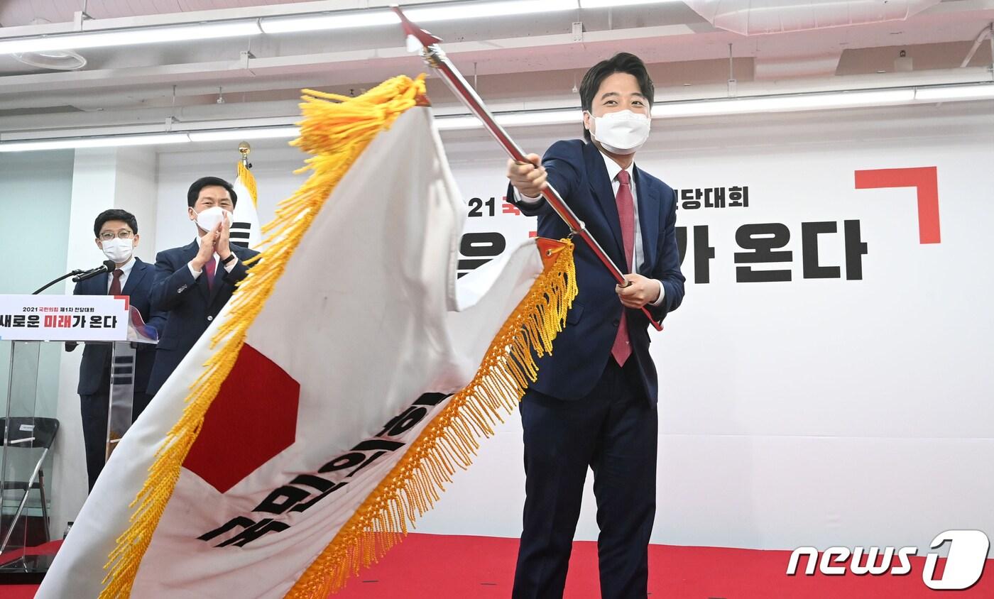 본문 이미지 - 이준석 국민의힘 신임 대표가 11일 오전 서울 영등포구 국민의힘 당사에서 열린 전당대회에서 당기를 흔들고 있다. '30대·0선'의 이 대표는 역대급 전당대회 흥행을 주도한 끝에 헌정사상 최초의 30대 보수정당 대표에 올랐다. 2021.6.11/뉴스1 ⓒ News1 오대일 기자