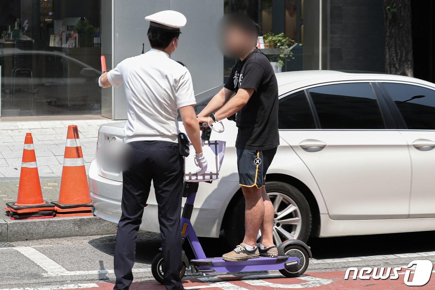 본문 이미지 - 개인형 이동장치(PM) 운전자의 안전 강화를 위한 도로교통법 개정안이 시행된 13일 오후 서울 시내에서 경찰이 헬멧을 미착용한 공유형 전동 킥보드를 이용자를 단속하고 있다. 2021.6.13/뉴스1 ⓒ News1 성동훈 기자