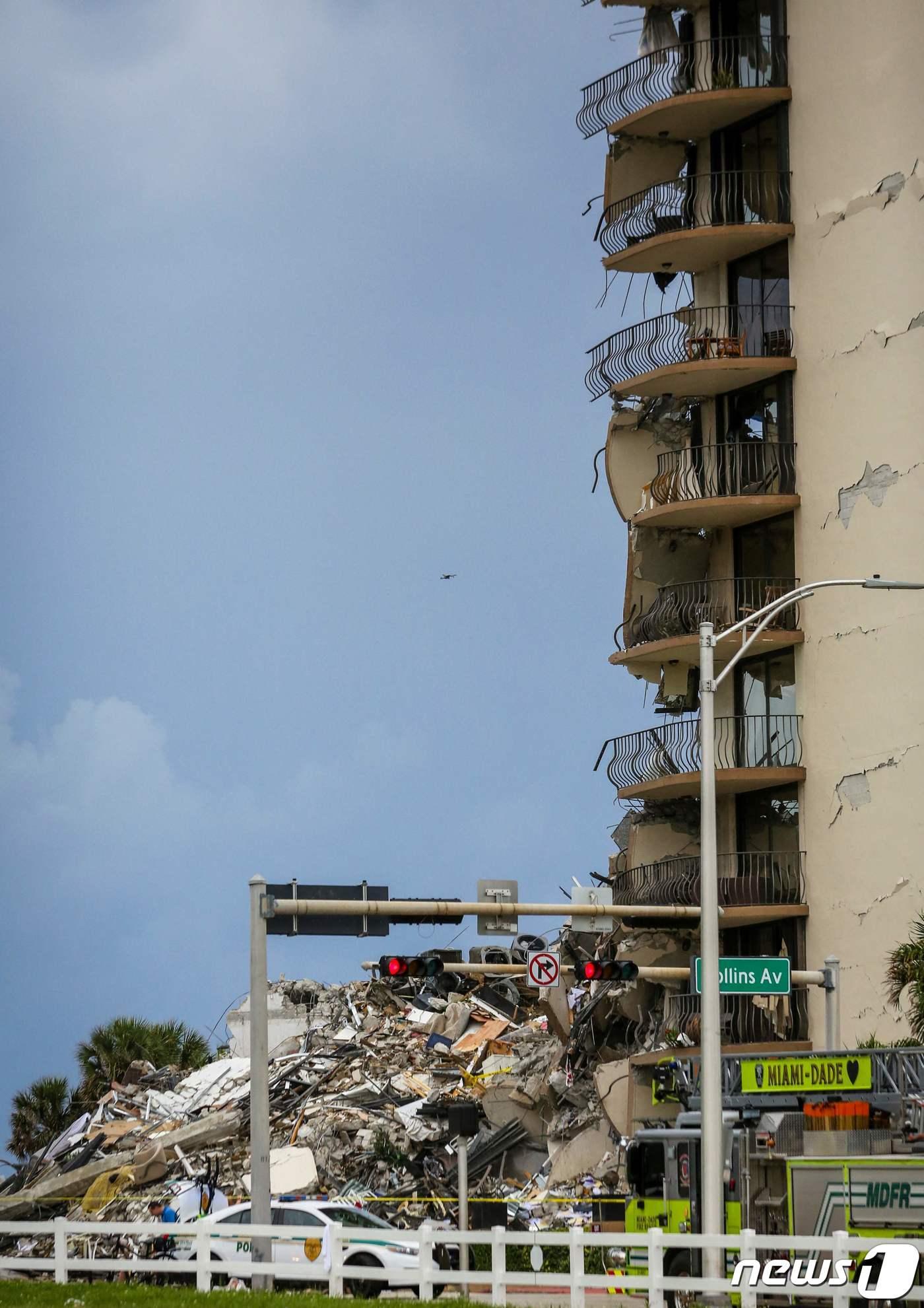 본문 이미지 - 24일(현지시간) 플로리다주 마이애미의 서프사이드에 있는 12층 짜리 챔플레인 타워 콘도 건물이 폭격 맞은 듯 무너져 1명이 사망하고 99명이 실종된 현장의 모습이 보이고 있다. ⓒ AFP=뉴스1 ⓒ News1 우동명 기자