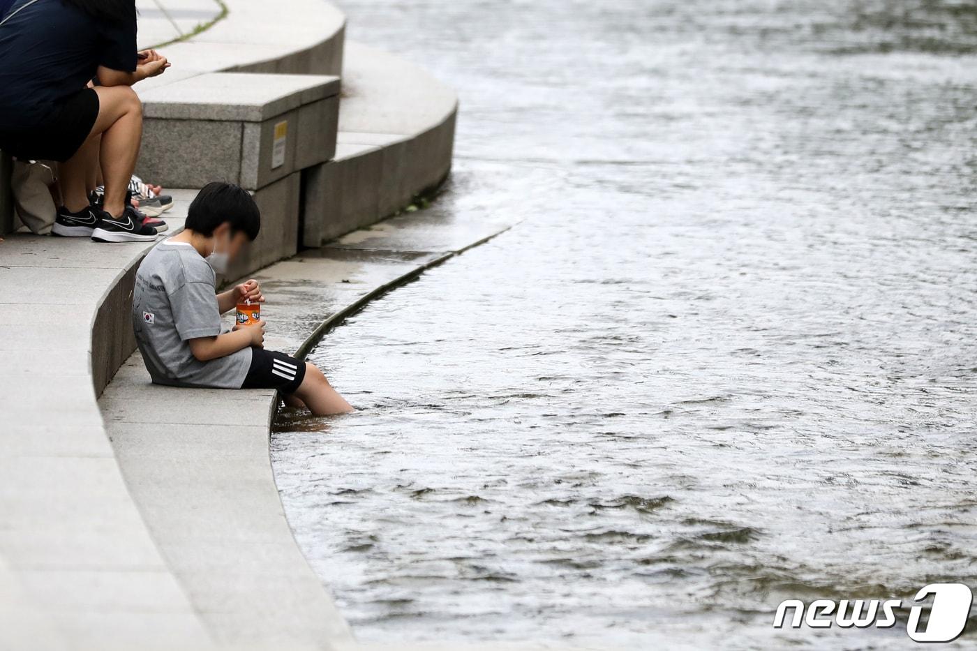  청계천을 찾은 학생이 물에 발을 담근채  더위를 식히고 있다. ⓒ News1 이승배 기자