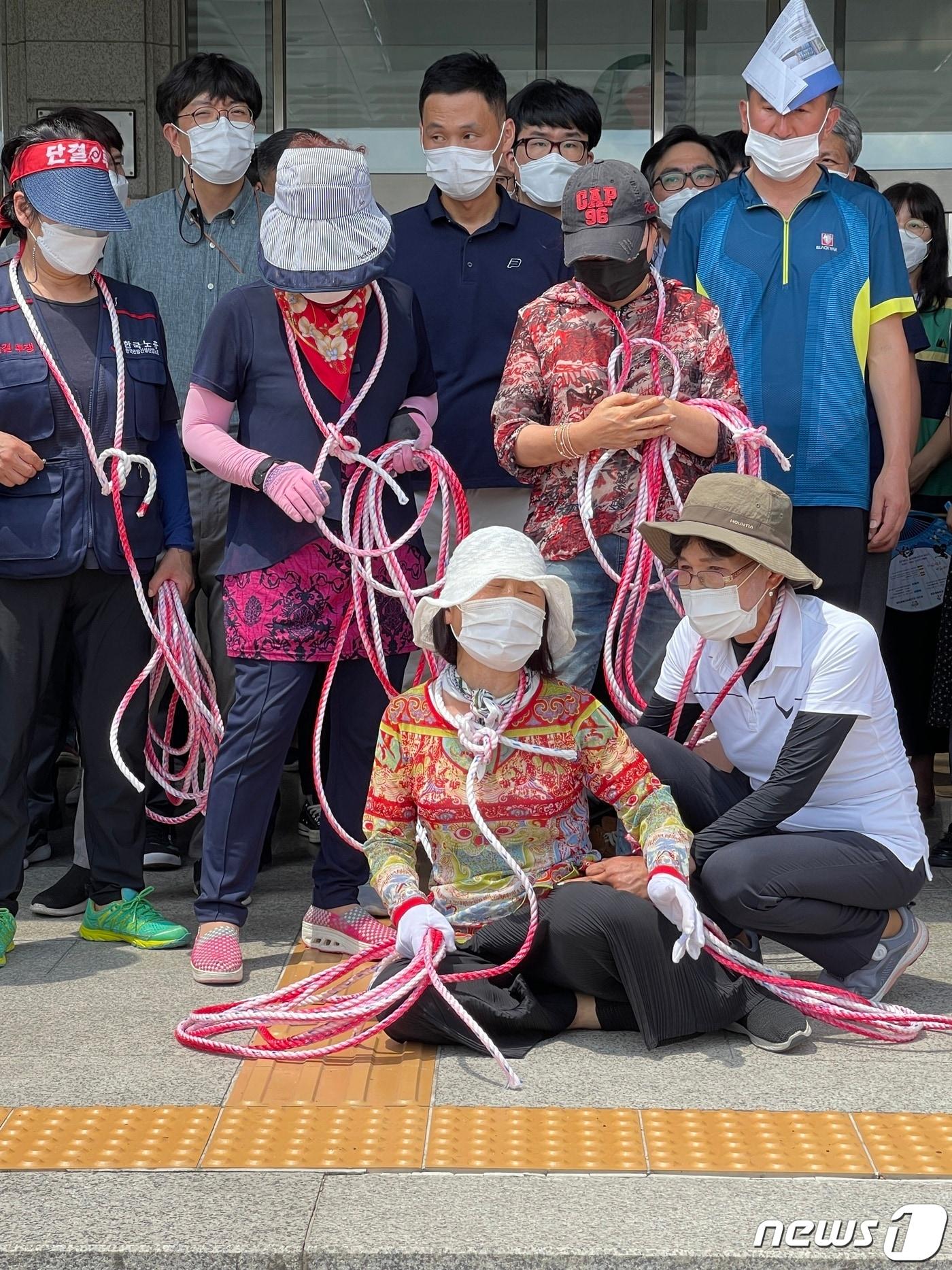본문 이미지 - 15일 충북 충주라이트월드 한 투자자가 이날 오후 2시 예고한 집단 투신이 무산되자 목에 밧줄을 걸고 나타나 충주시에 보상을 요구하며 울부짖고 있다.2021.7.15/ⓒ 뉴스1