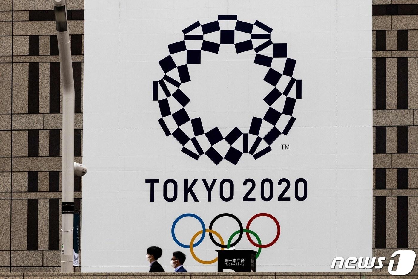 마스크를 착용한 시민들이 도쿄 올림픽 엠블럼 앞을 지나가고 있다.  ⓒ AFP=뉴스1