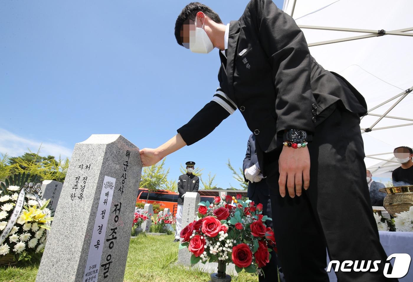 본문 이미지 - 지난 7월23일 '천안함 전사자' 고(故) 정종율 상사의 배우자 정경옥씨의 안장식이 국립대전현충원 천안함 46용사 묘역에서 엄수됐다. 고인의 아들 정모군이 부모의 묘비를 만지고 았다. 2021.7.23/뉴스1 ⓒ News1 김기태 기자
