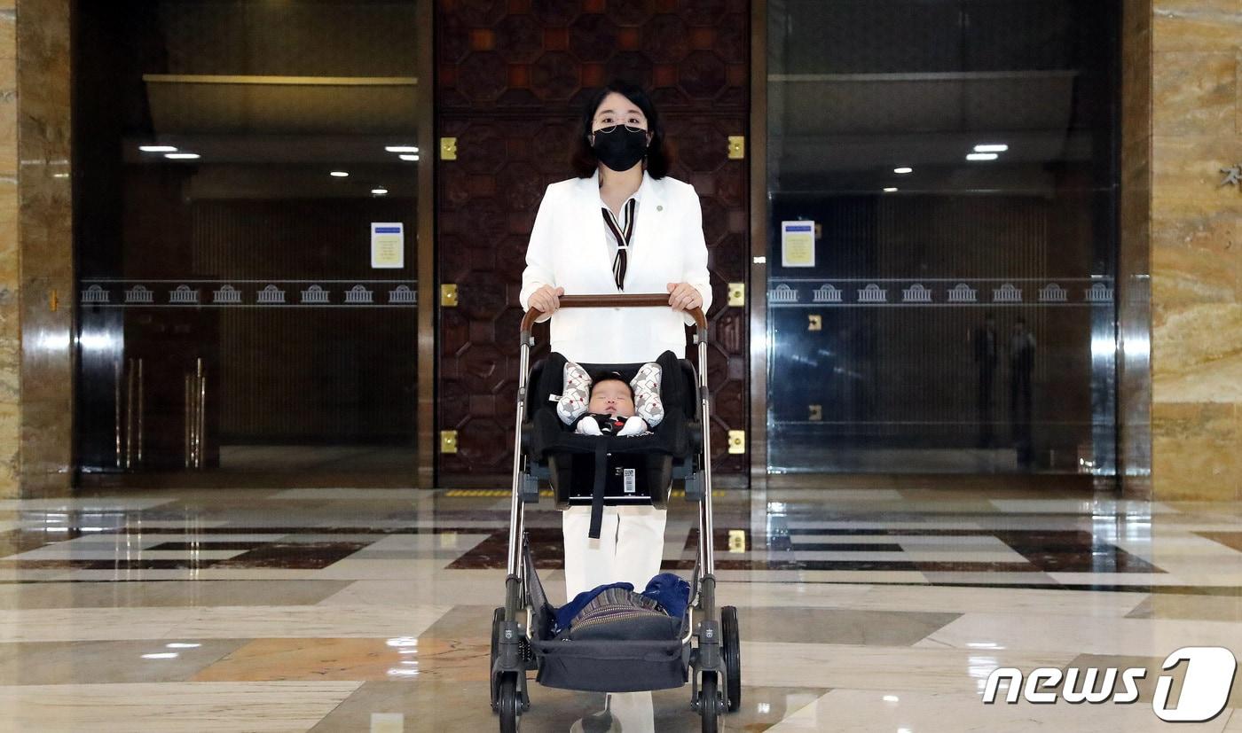 본문 이미지 - 당시 출산휴가를 마치고 국회에 복귀한 용혜인 기본소득당 의원이 아들과 함께 서울 여의도 국회 본회의장 앞을 지나고 있다. 2021.7.5 ⓒ 뉴스1 구윤성 기자