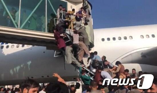 본문 이미지 - 16일&#40;현지시간&#41; 시민들이 아프가니스탄 탈출을 위해 찾은 카불 국제공항에서 비행기에 올라타고 있다. &#40;트위터 캡쳐&#41; 2021.8.16/뉴스1 ⓒ News1 이성철 기자