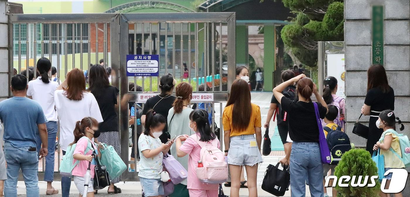 본문 이미지 - 23일 서울의 한 초등학교에서 개학을 맞은 어린이들이 보호자와 함께 등교하고 있다. 2021.8.23/뉴스1 ⓒ News1 민경석 기자