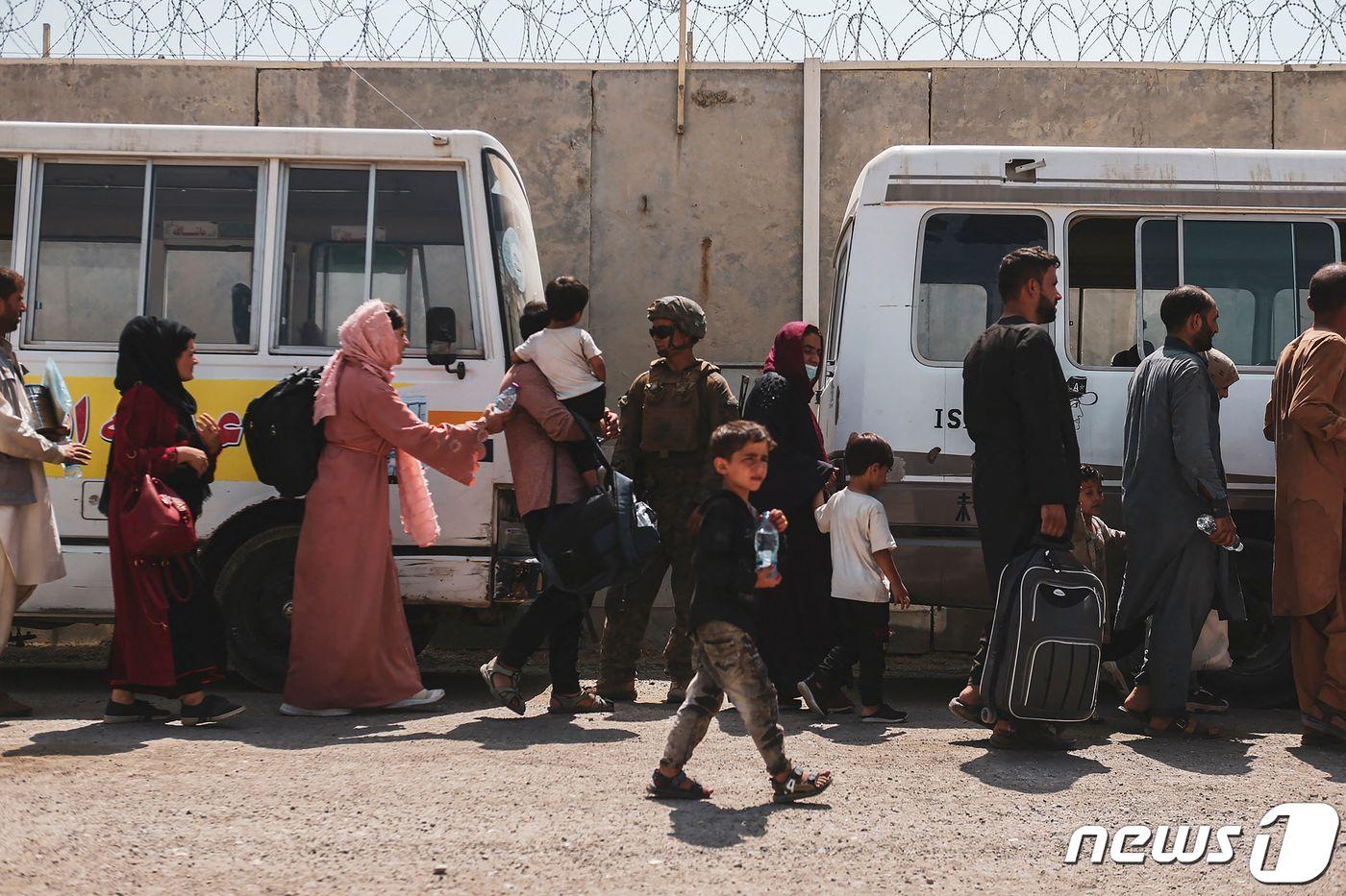 22일(현지시간) 카불에서 아프가니스탄 난민들이 하미다 카르자이 국제공항에서 환승 버스를 기다리고 있다. ⓒ AFP=뉴스1 ⓒ News1 구진욱 기자