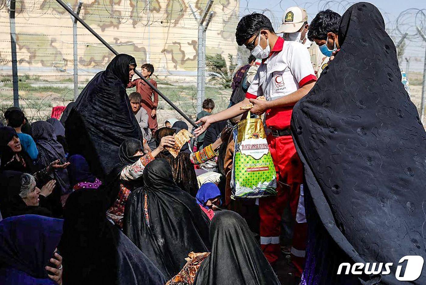19일(현지시간) 이란 적십자 단체가 아프간-이란 접경지대 피난민들에게 구호 물품을 배급하고 있다. 2021.08.19 ⓒ AFP=뉴스1