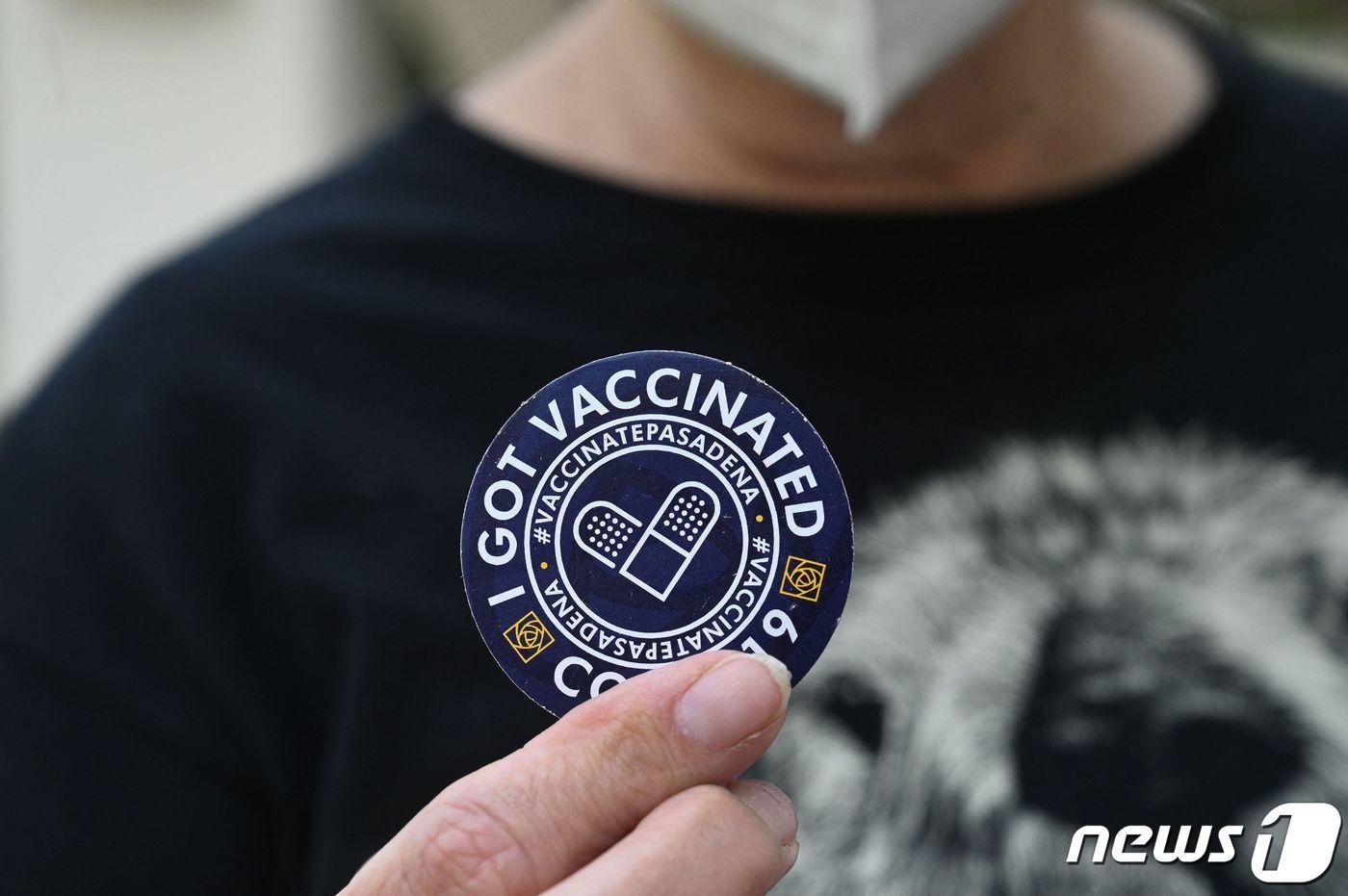 미국 캘리포니아에서 2021년 8월 19일 한 여성이 코로나19 백신 3차 접종을 맞은 뒤 접종 확인 스티커를 들어 보이고 있다. 미국 식품의약국(FDA)은 지난 12일 면역력 취약군에 대한 추가 접종을 승인한 데 이어, 내달 20일부터는 전 국민을 대상으로 부스터샷을 실시한다는 방침이다.  ⓒ AFP=뉴스1