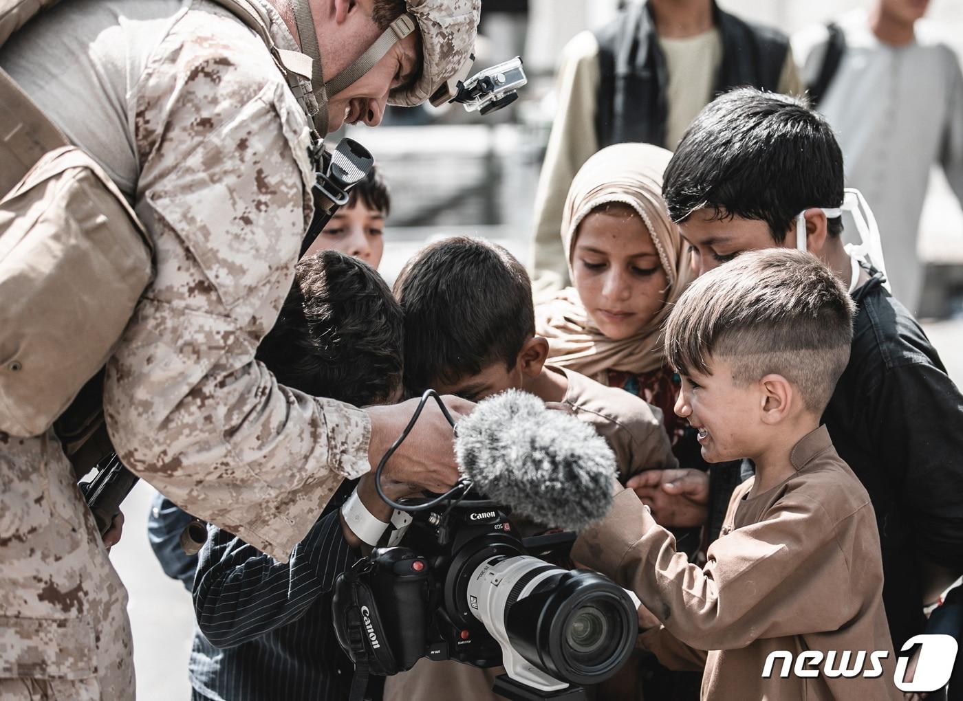 본문 이미지 - 아프가니스탄 하미드 카르자이 국제공항에서 지난 22일(현지시간) 피난을 기다리는 아이들이 미군의 비디오 카메라를 보며 해맑게 웃고 있다. ⓒ 로이터=뉴스1 ⓒ News1 최서윤 기자