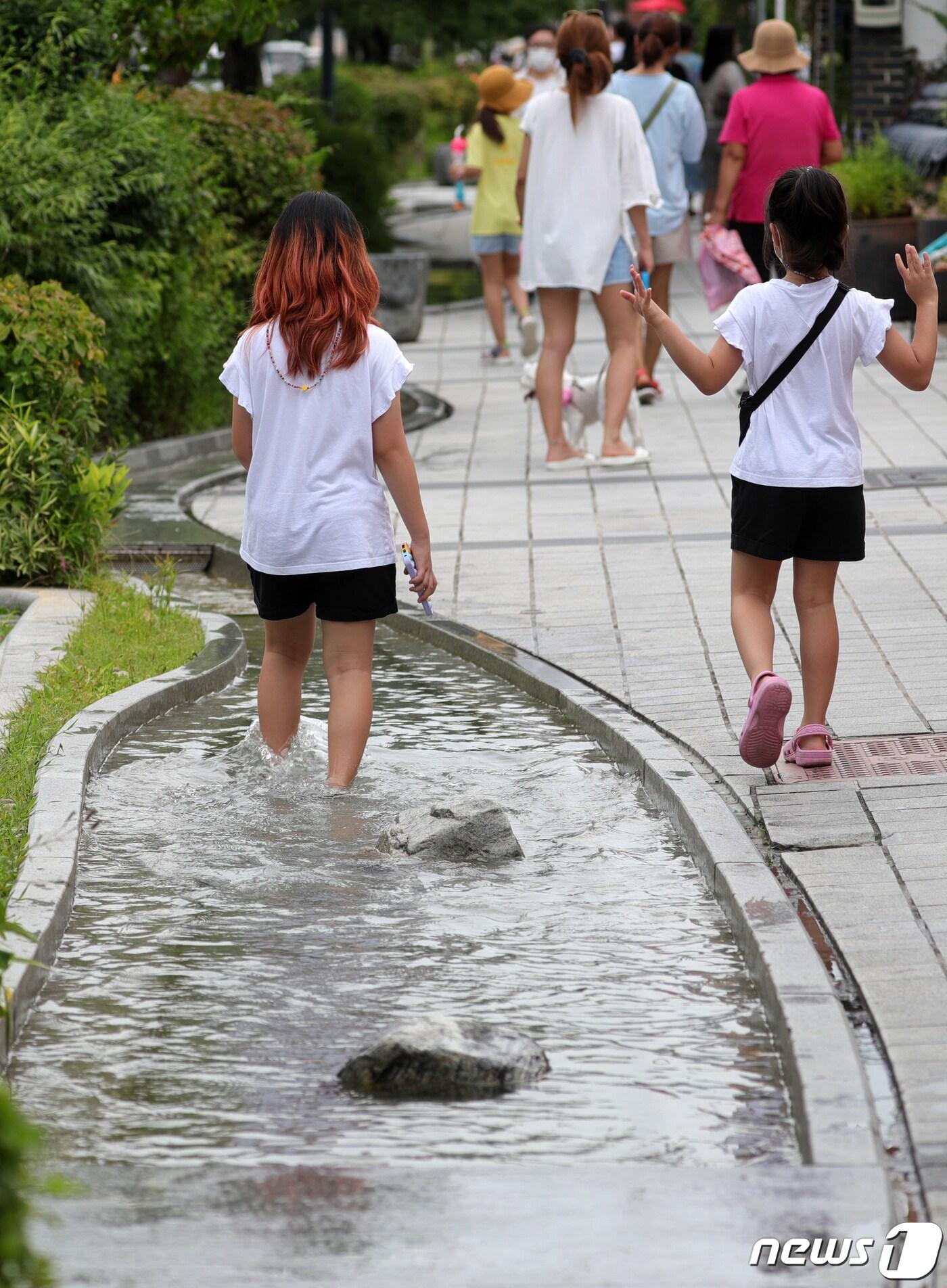 본문 이미지 - 휴가철을 맞아 전북지역 대표관광지인 전주 한옥마을에 관광객들의 발길이 이어지고 있는 3일 전주 한옥마을에서 한 어린이가 인공 실개천에 발을 담근 채 걷고 있다. 2021.8.3/뉴스1 ⓒ News1 유경석 기자
