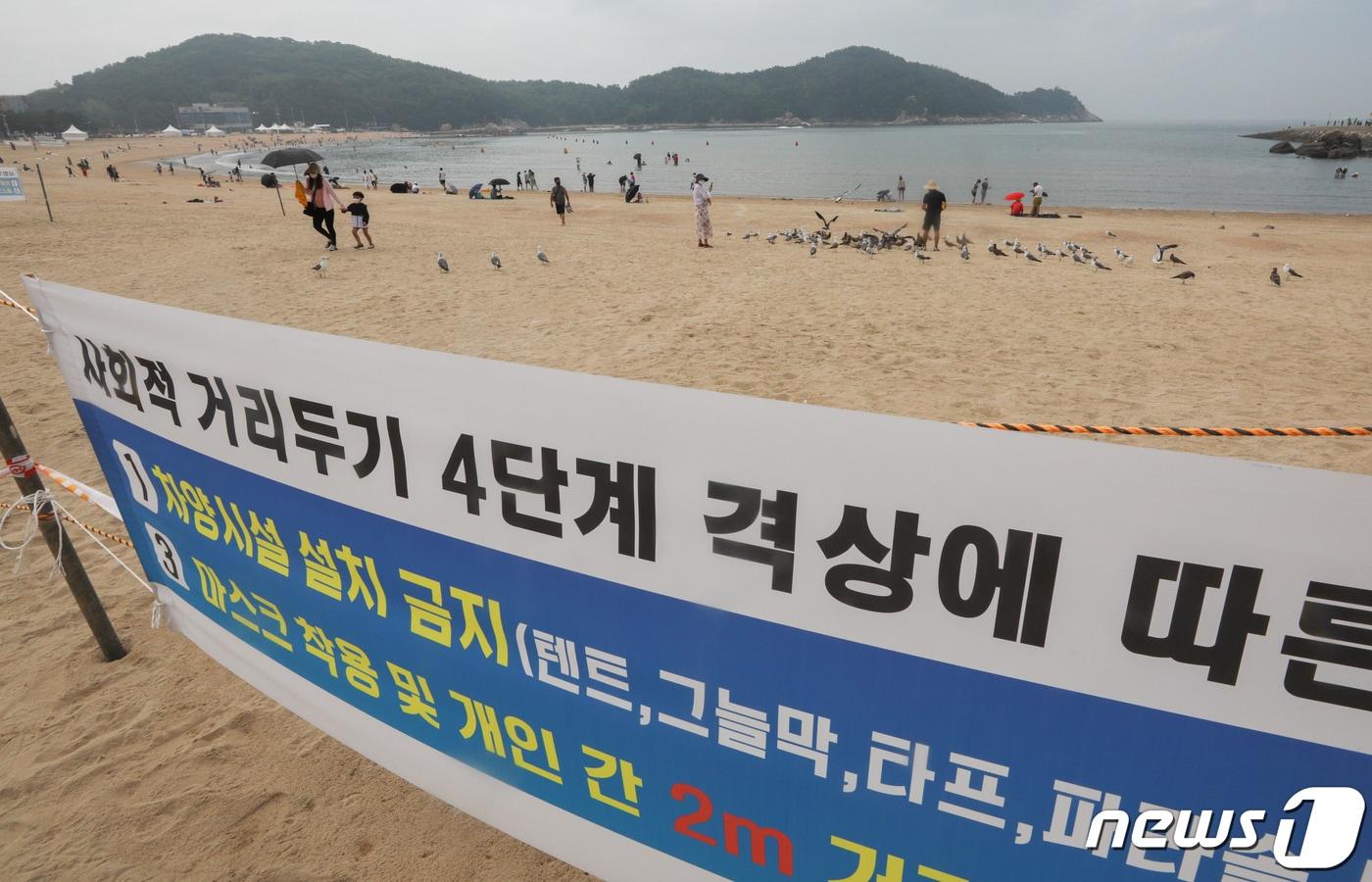 본문 이미지 - 본격적인 휴가철을 맞은 지난 3일 오전 인천광역시 중구 을왕리해수욕장에서 거리두기 방역수칙 안내 플래카드 뒤로 피서객들이 물놀이를 즐기거나 모래사장에서 휴식을 취하고 있다. 2021.8.3 /뉴스1 ⓒ News1 성동훈 기자