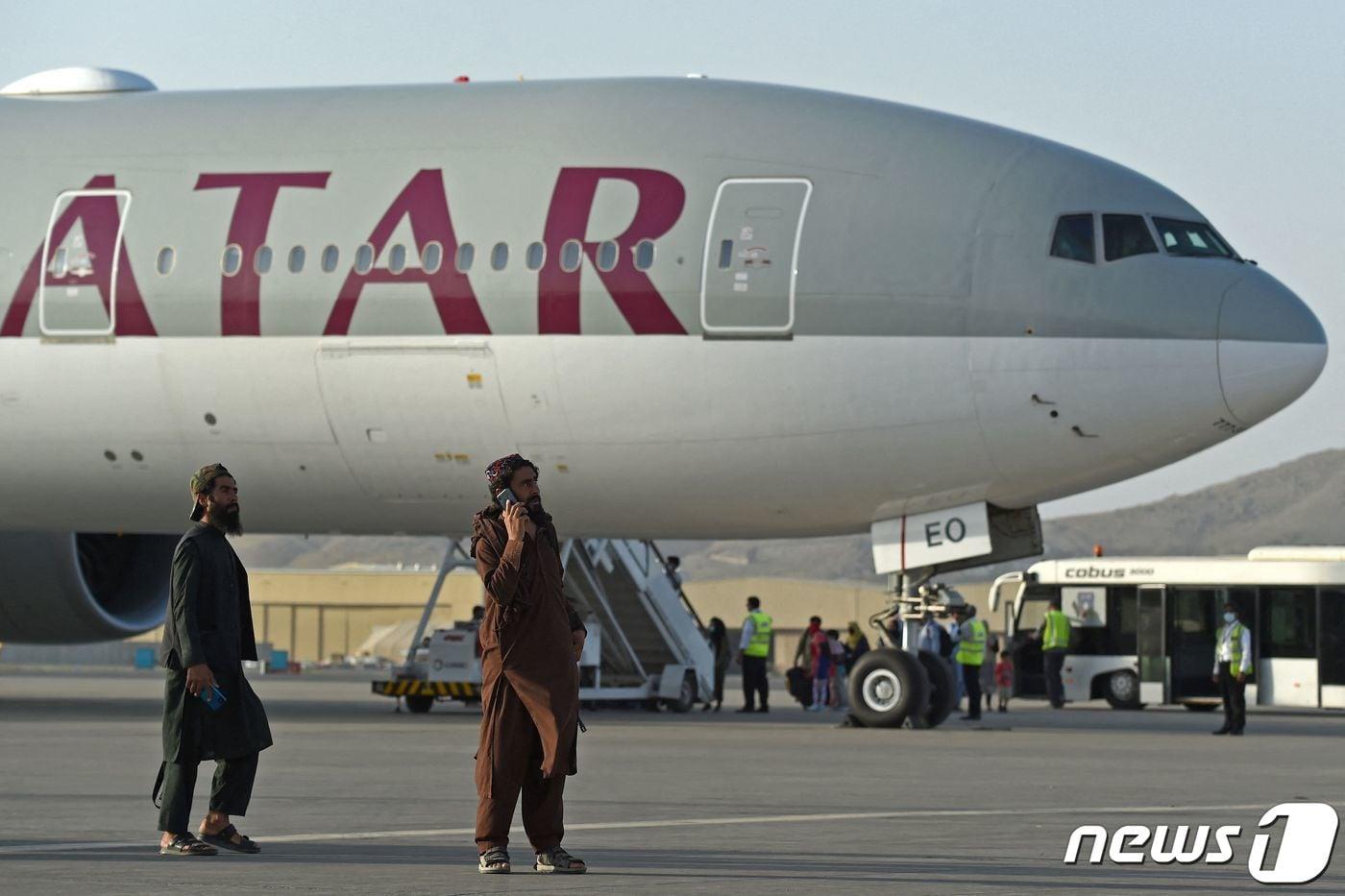 본문 이미지 - 미국인 등 승객 200명이 9일(현지시간) 아프가니스탄 카불 공항에서 카타르 항공기에 오르는 동안 탈레반 조직원들이 경비를 서고 있다. 지난달 30일 밤 11시59분 마지막 미 군 수송기가 떠난 이후 첫 탈출 비행이다. ⓒ AFP=뉴스1 ⓒ News1 안은나 기자